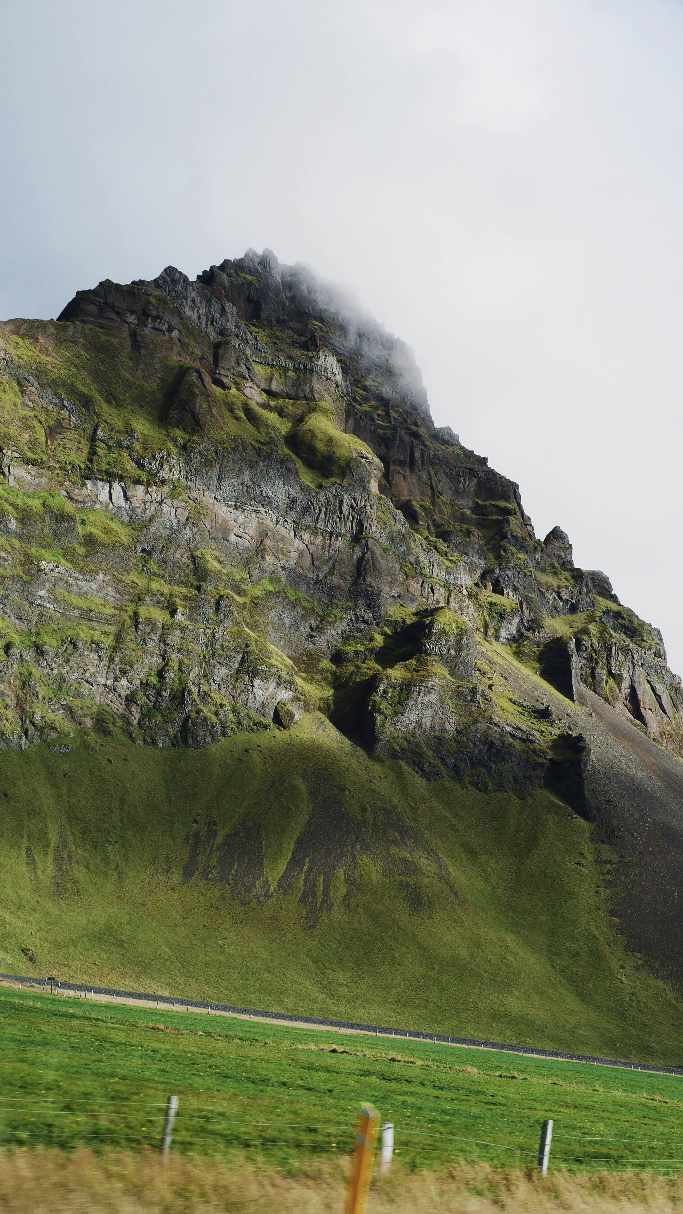 Green mountain with rocky peak and fog HD Wallpaper