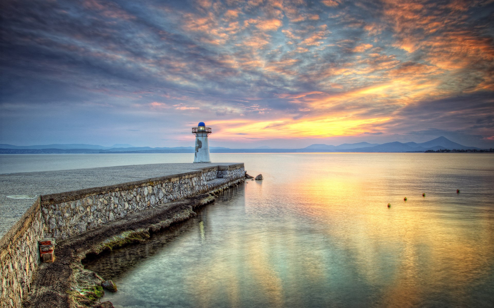 Lighthouse on a stone pier at sunset HD Wallpaper