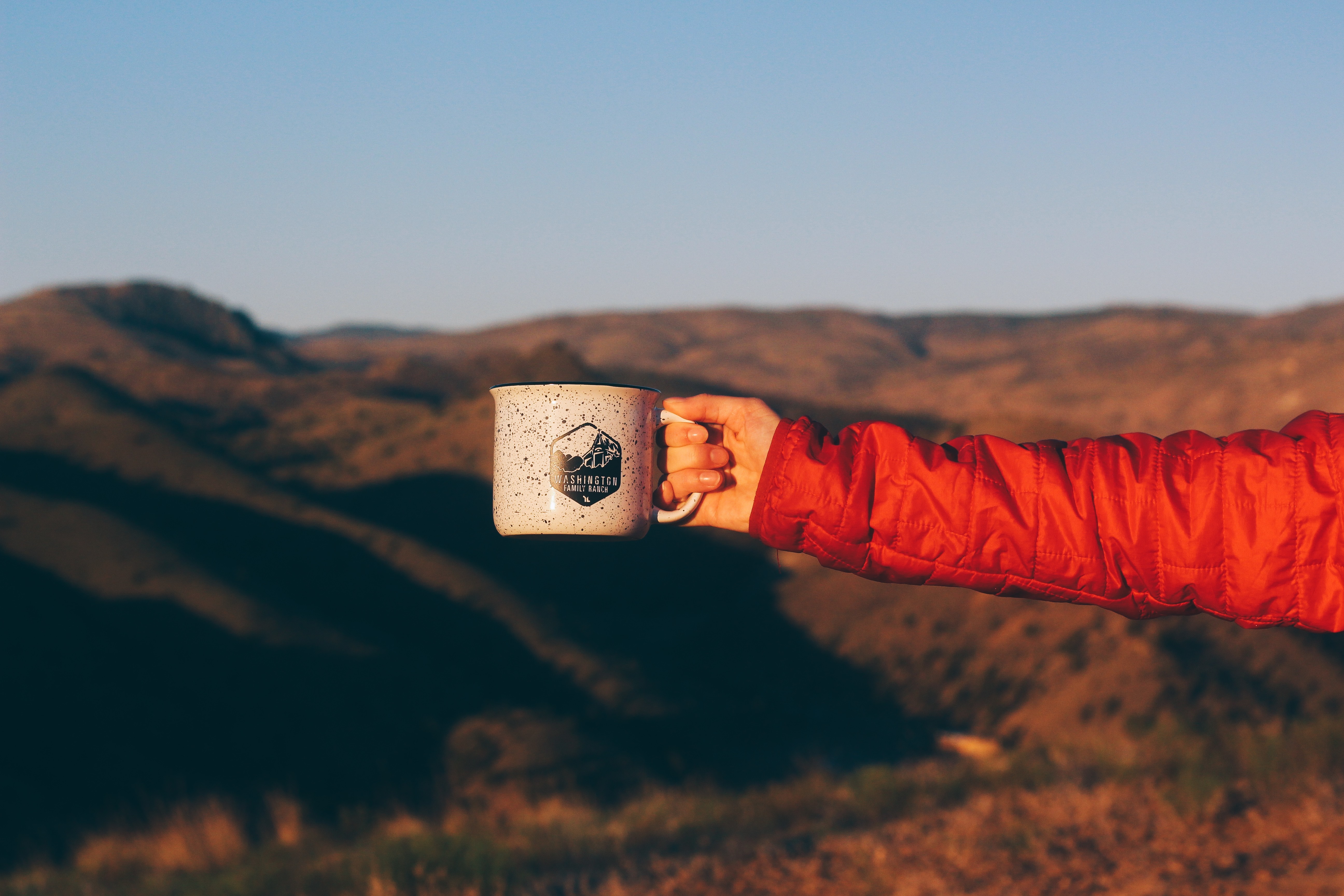 Hand holding a mug with mountains in the background HD Wallpaper