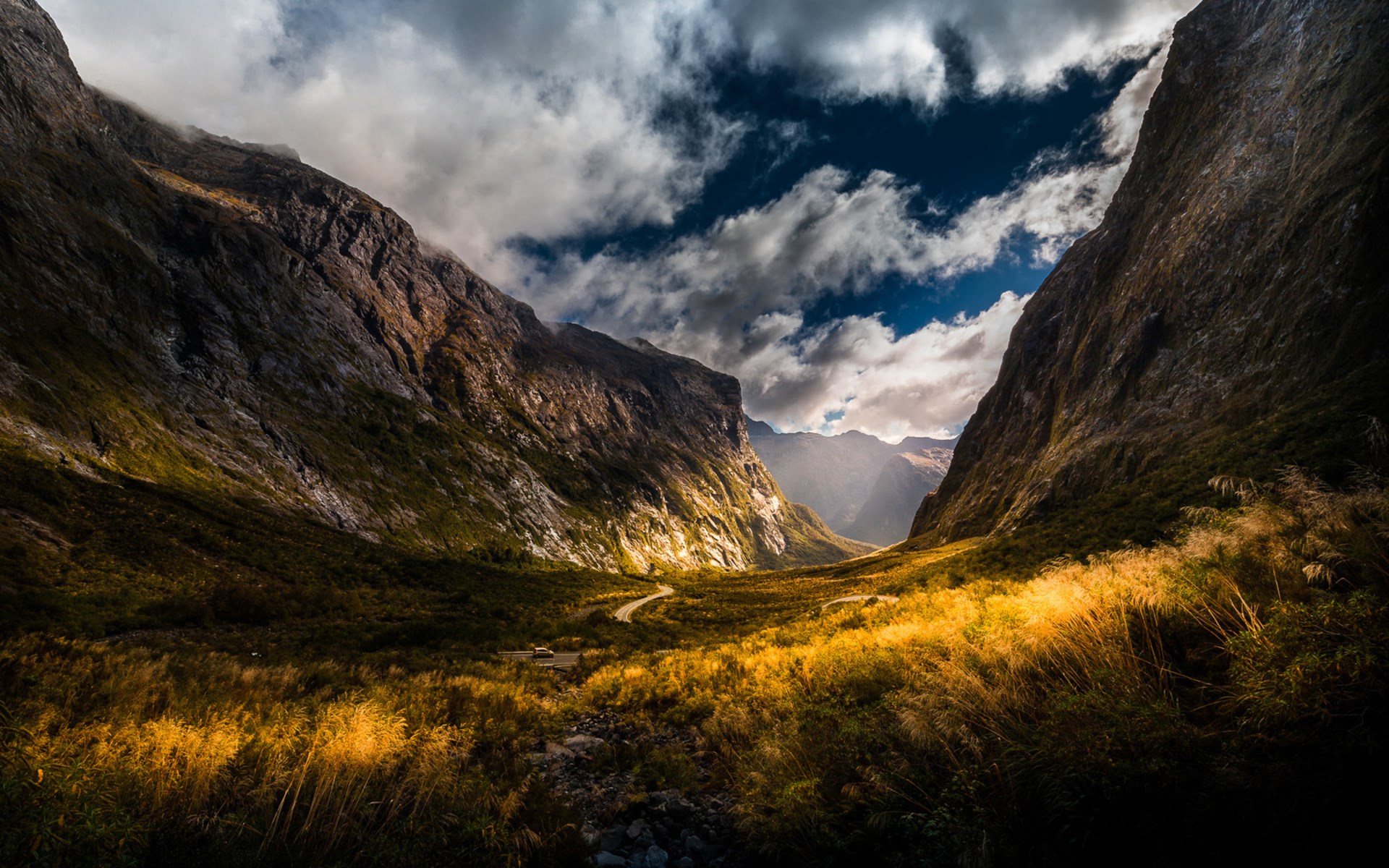 Mountain valley with a winding road and golden grass HD Wallpaper