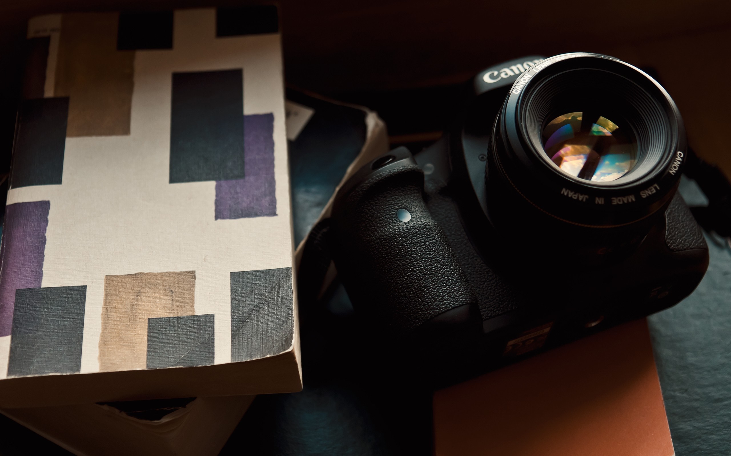 Canon DSLR camera and book with abstract cover HD Wallpaper