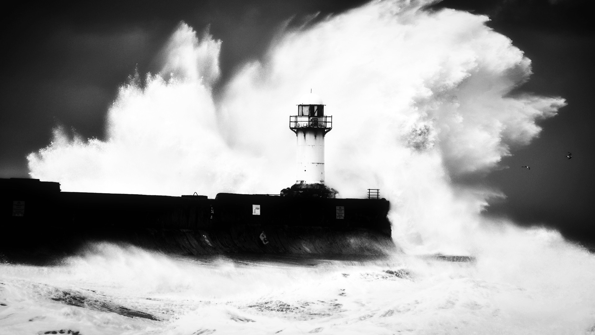 Monochrome lighthouse on a pier with large waves HD Wallpaper