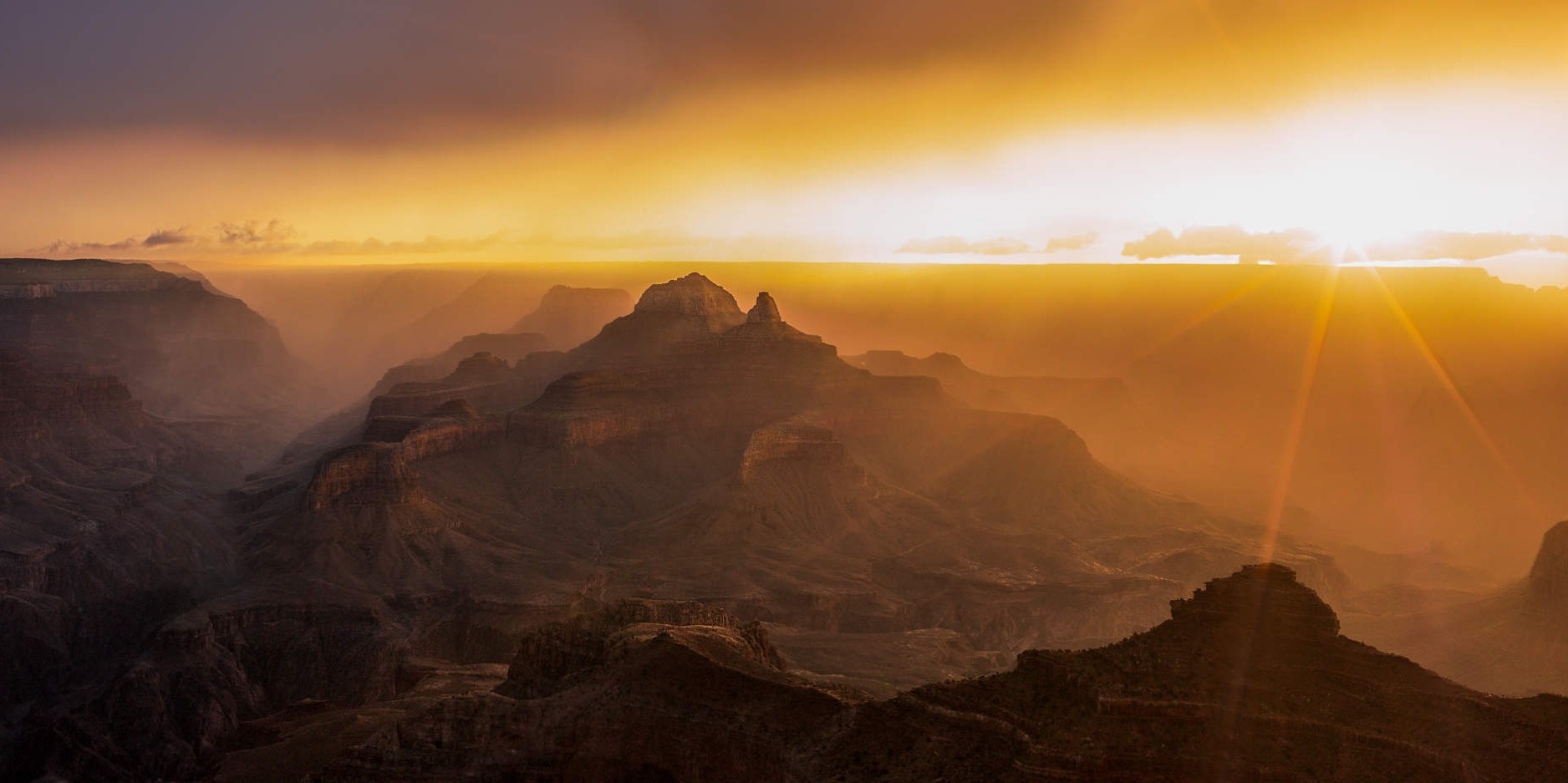 Grand Canyon at sunset with sun rays and mist HD Wallpaper