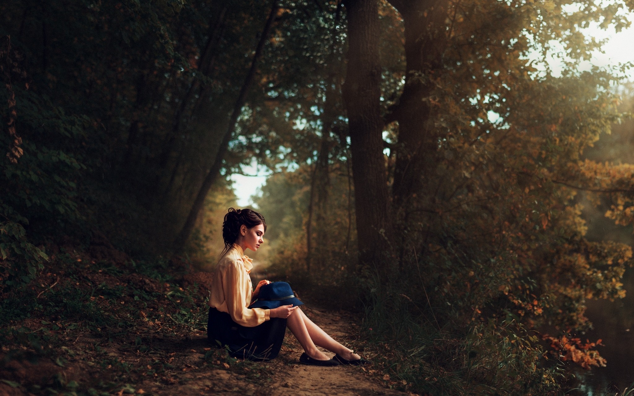 Woman in yellow shirt and skirt sitting in autumn forest HD Wallpaper