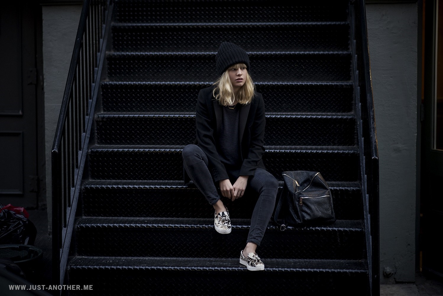 Lisa Dengler sitting on dark stairs with backpack HD Wallpaper