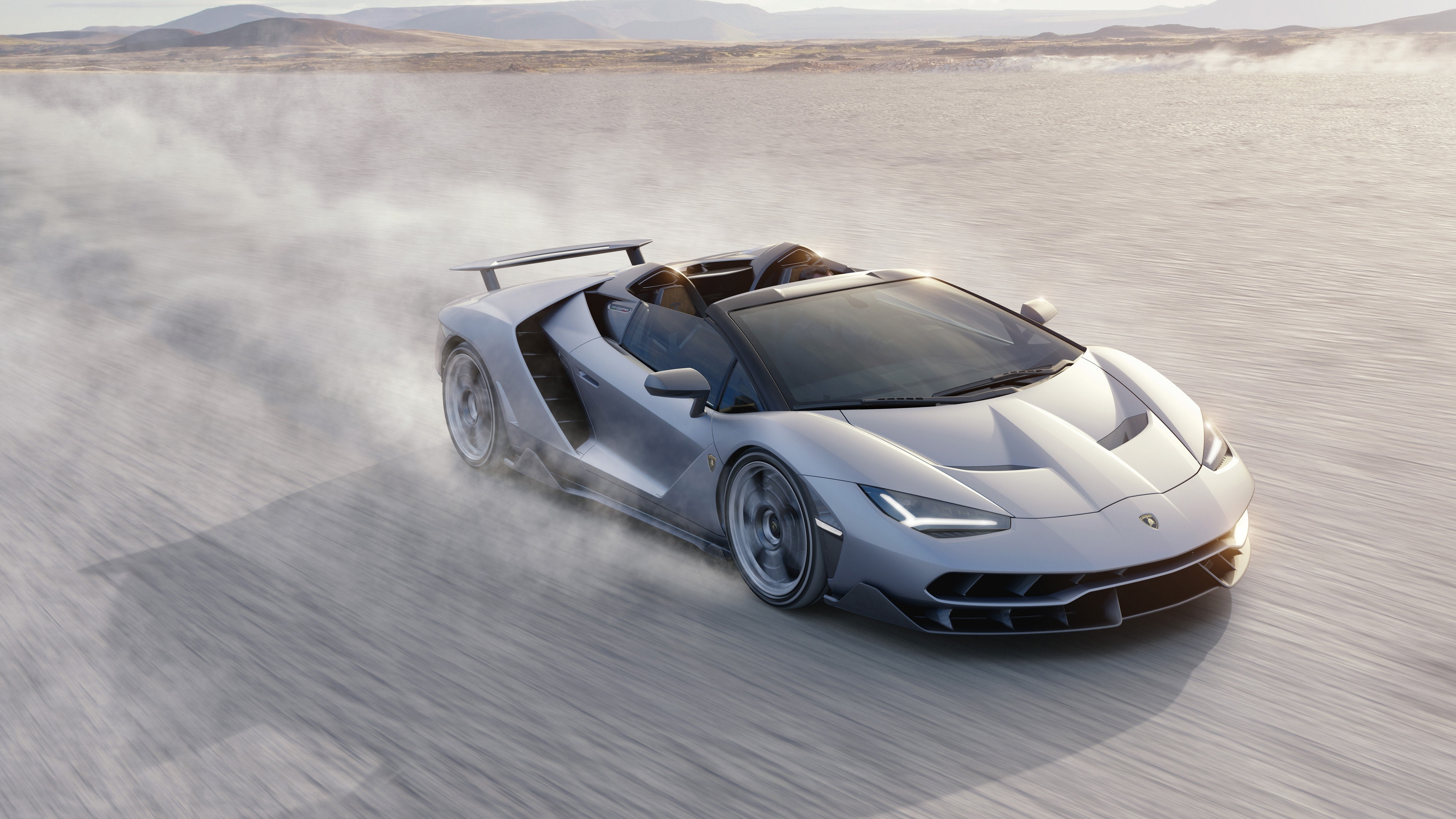 Lamborghini Centenario Roadster driving on a dusty plain HD Wallpaper