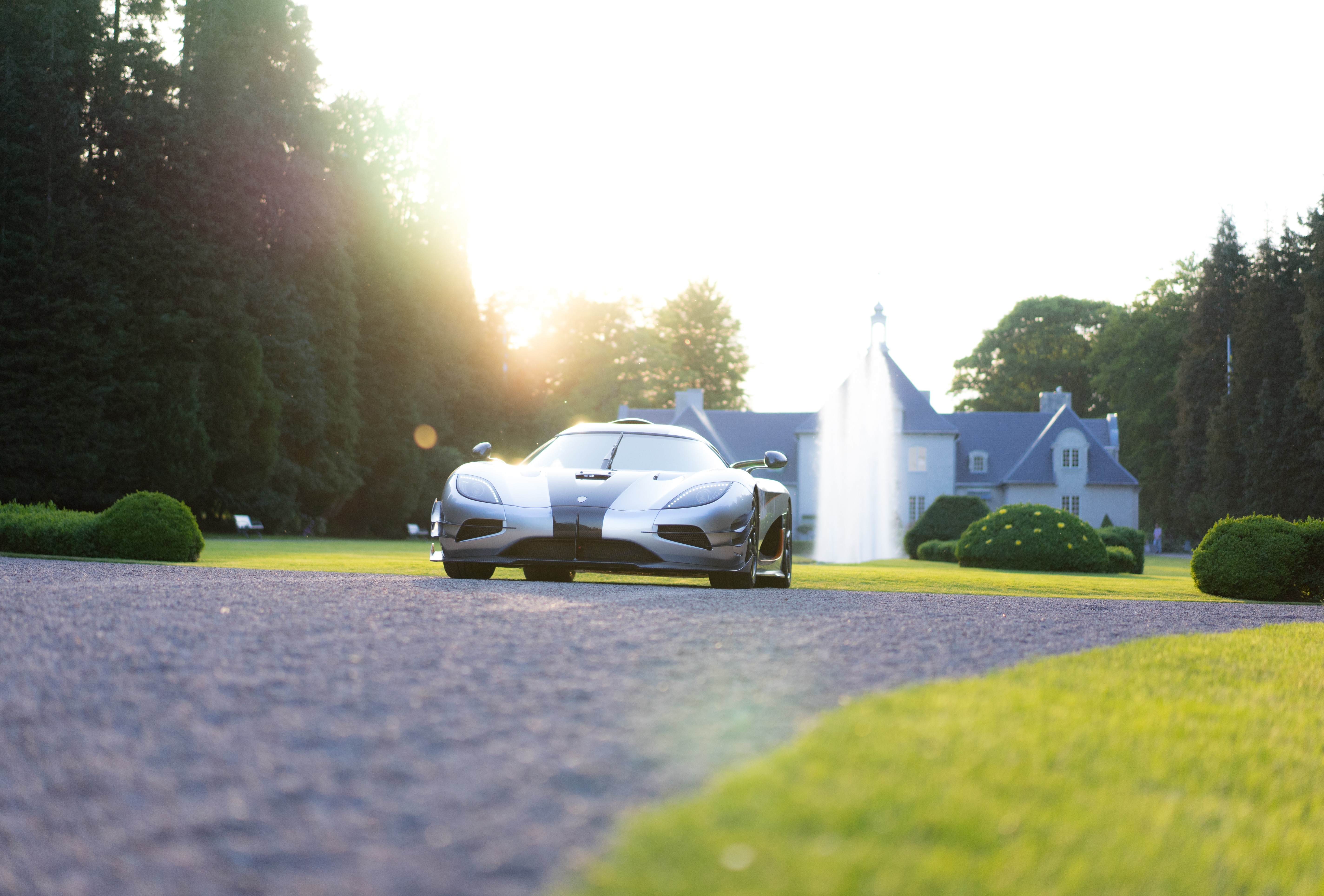 Koenigsegg sports car on driveway with mansion and fountain HD Wallpaper