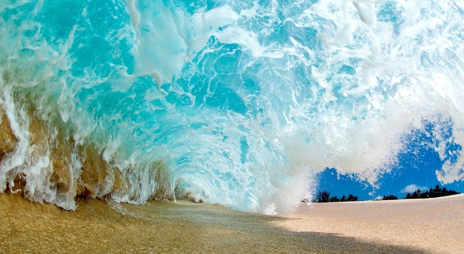 Wave crashing on a sandy beach with blue sky HD Wallpaper
