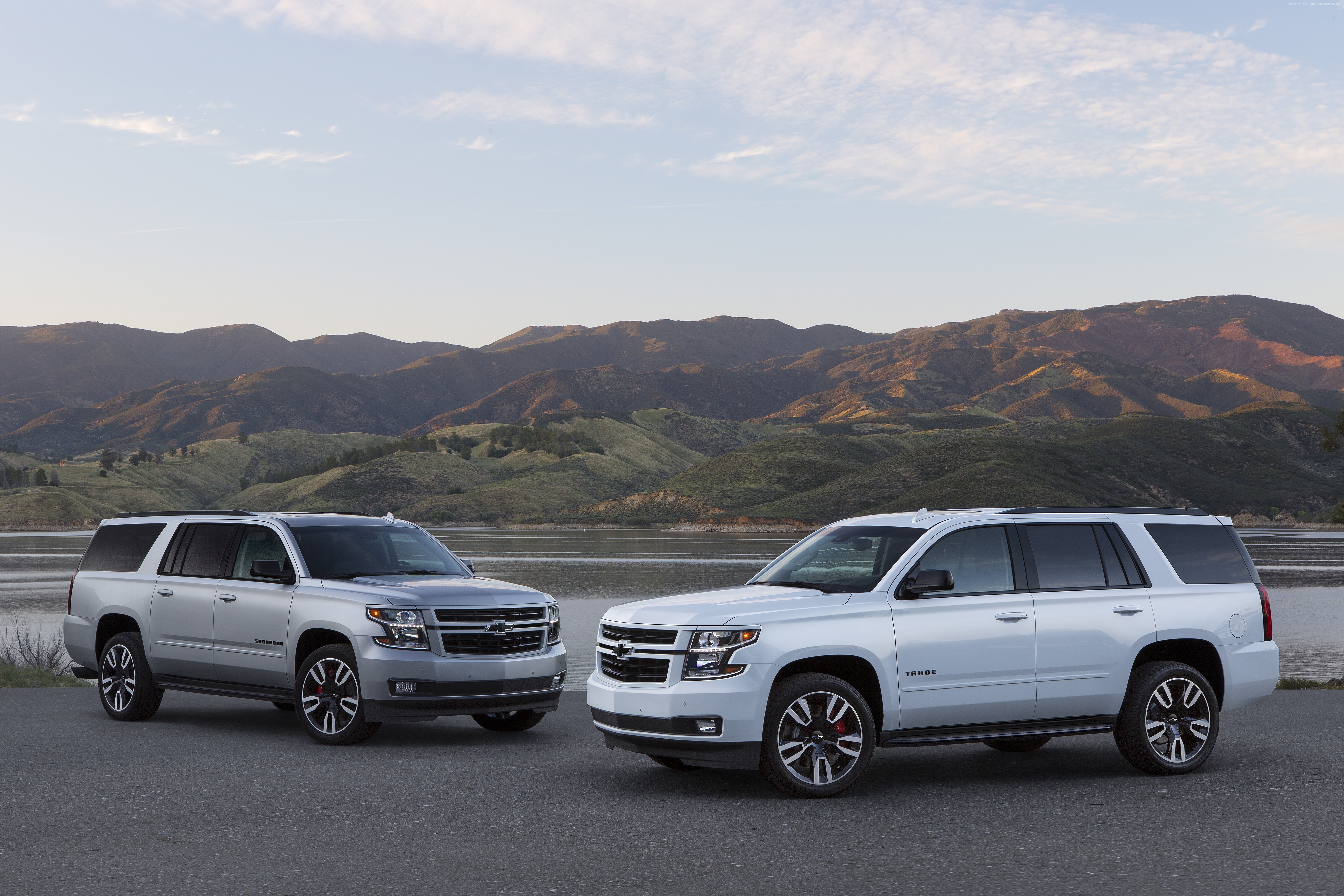 Two Chevrolet SUVs parked by a lake with mountains HD Wallpaper
