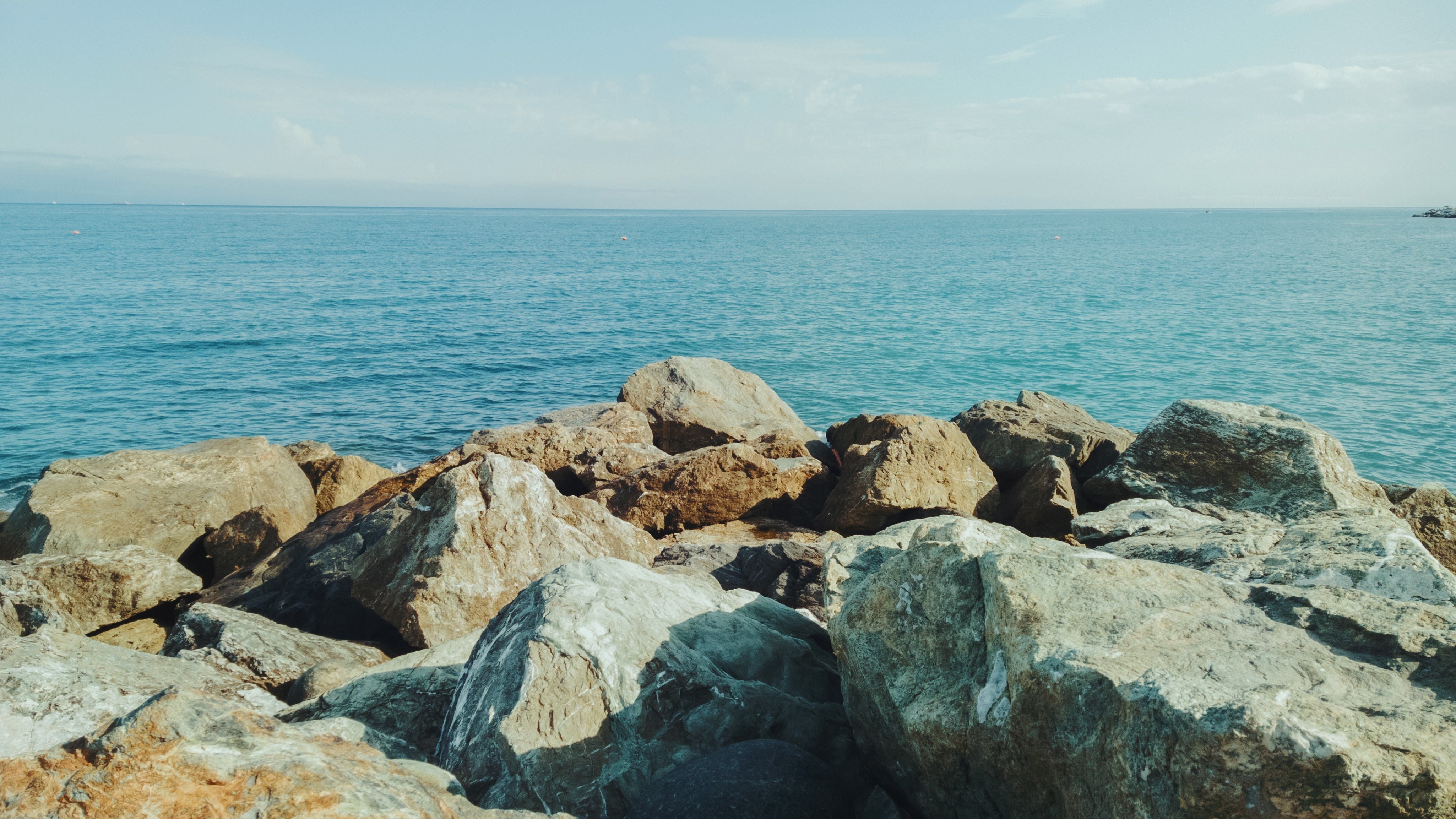 Rocks on the shore of the blue ocean under a clear sky HD Wallpaper