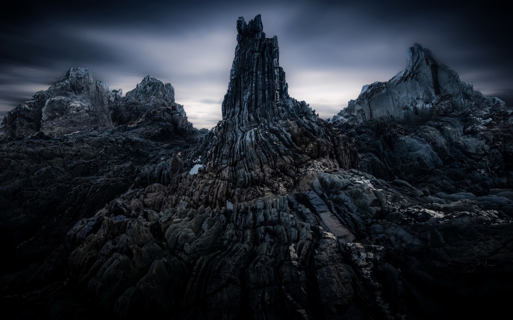 Dark rocky mountain landscape under a cloudy sky HD Wallpaper