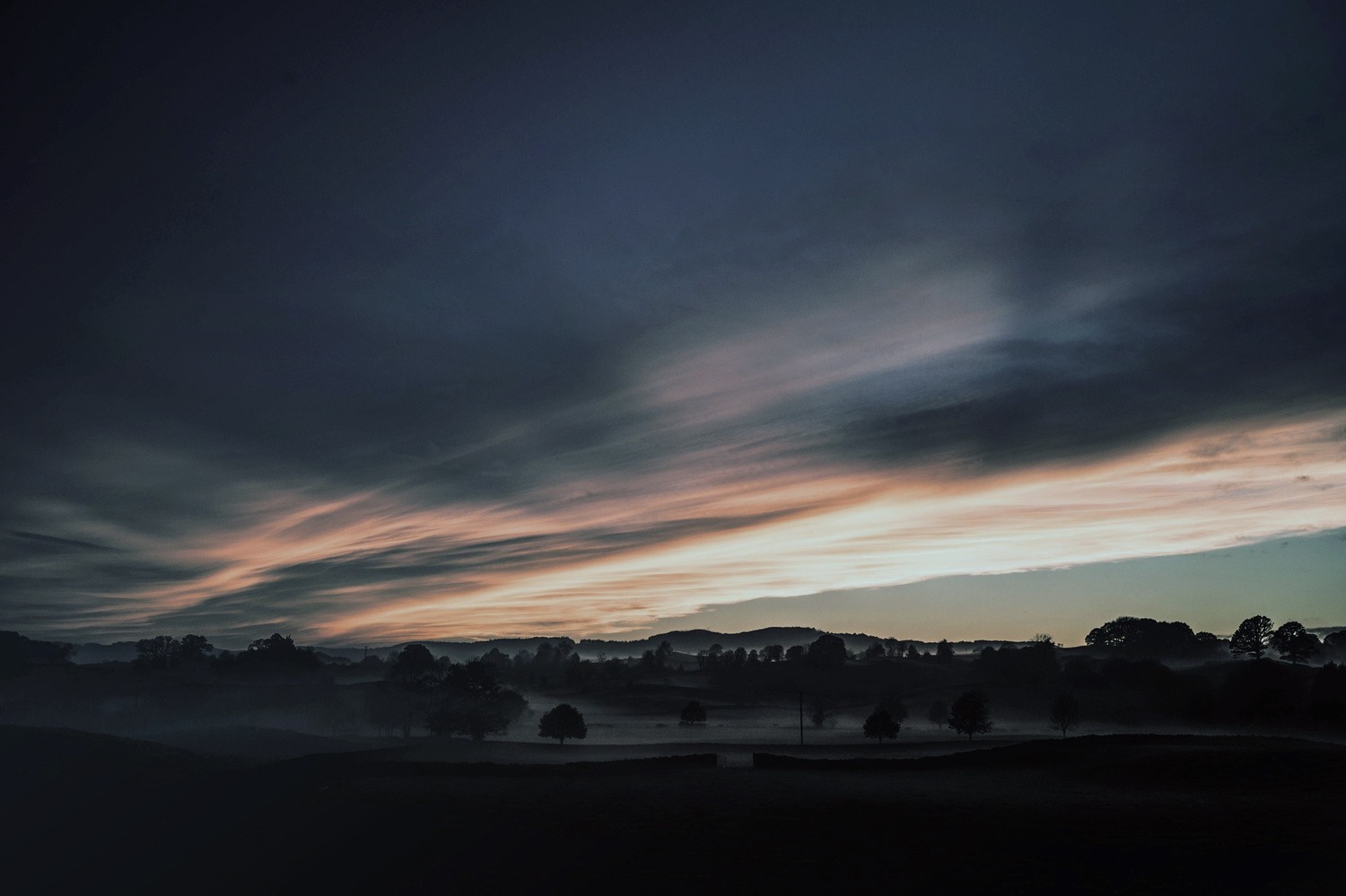 Sunset over misty countryside with dramatic clouds HD Wallpaper