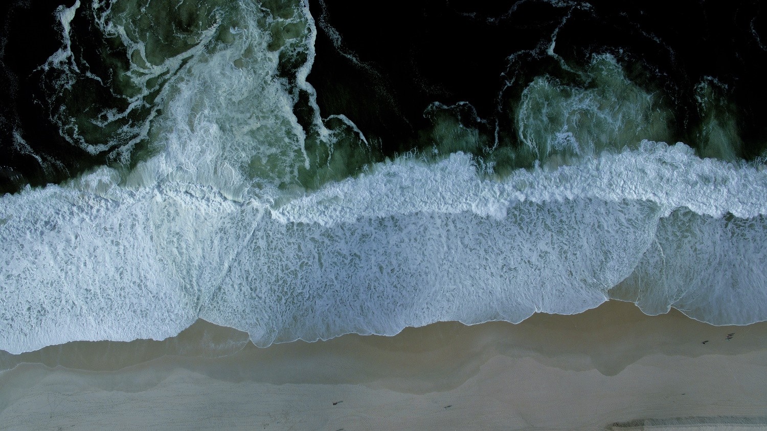 Aerial view of ocean waves crashing on a sandy beach HD Wallpaper