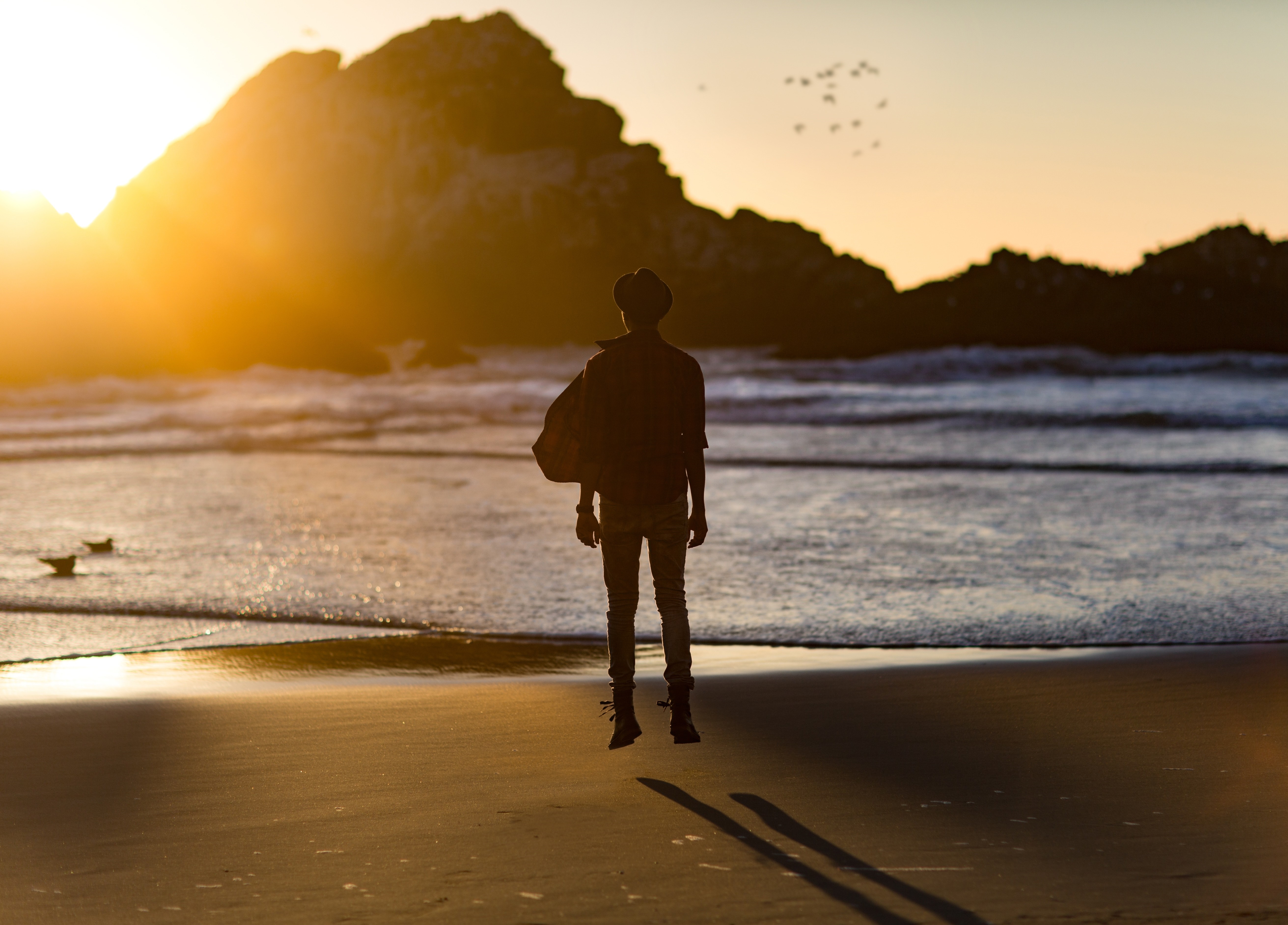 Person jumping on a beach at sunset HD Wallpaper