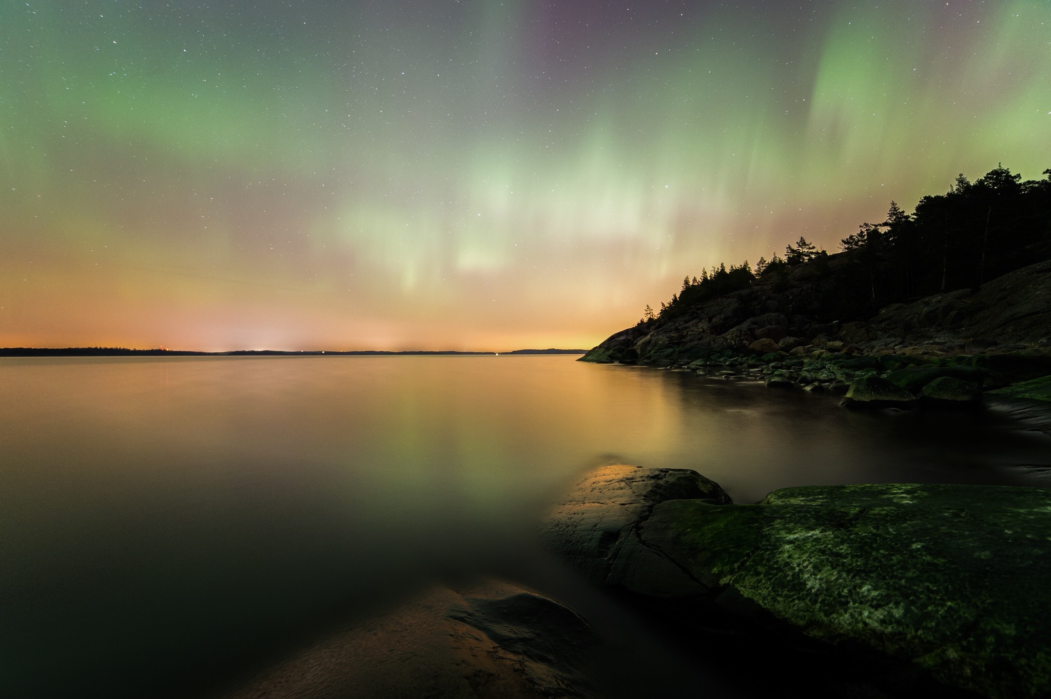 Aurora Borealis over a calm lake and rocky shore HD Wallpaper