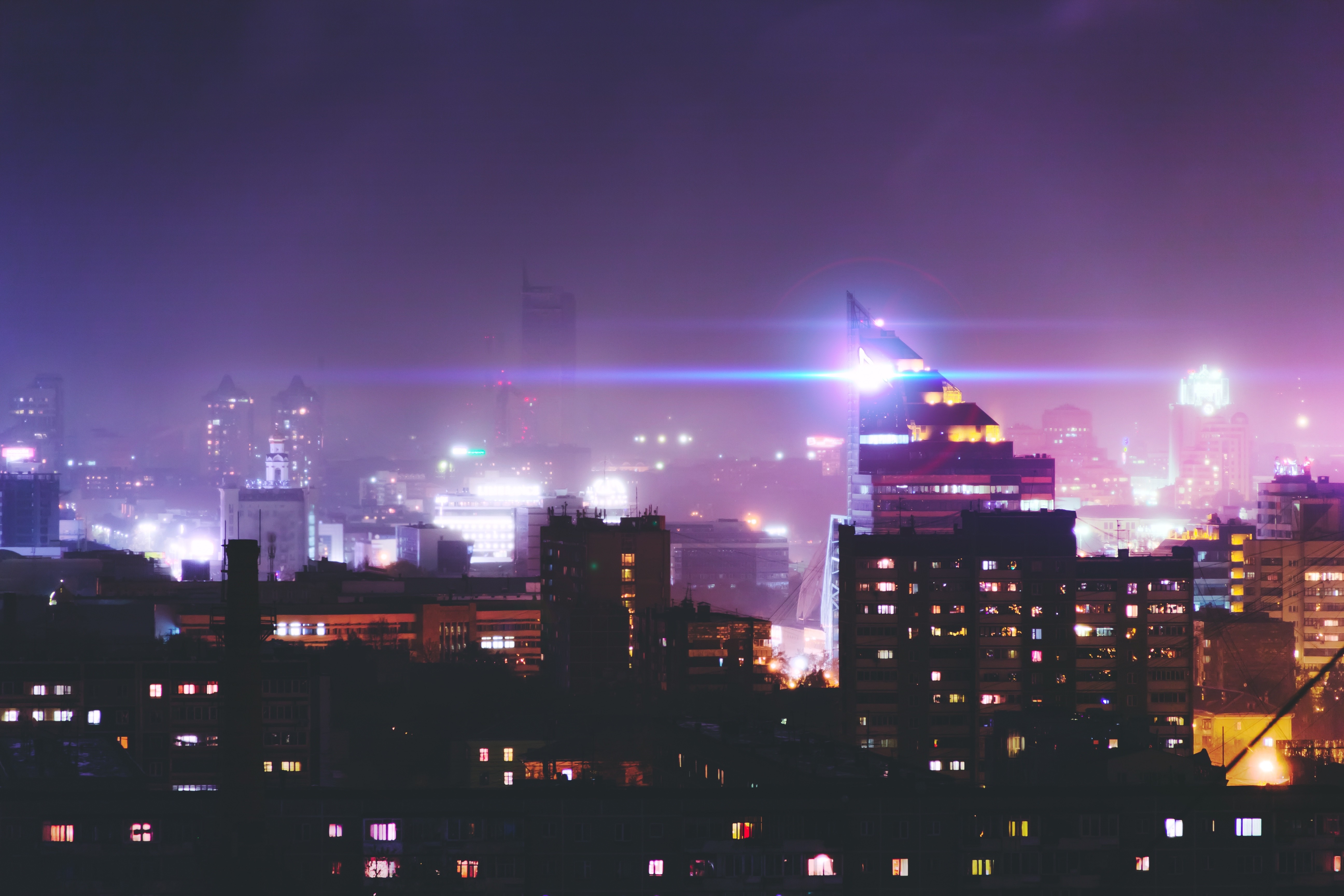 Cityscape at night with glowing buildings and lens flare HD Wallpaper