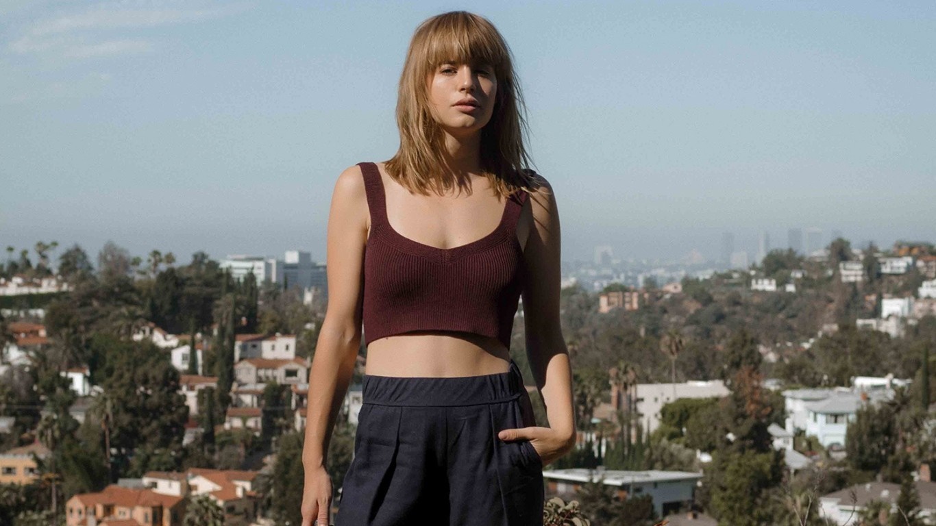 Woman with bangs in a burgundy crop top and navy pants HD Wallpaper