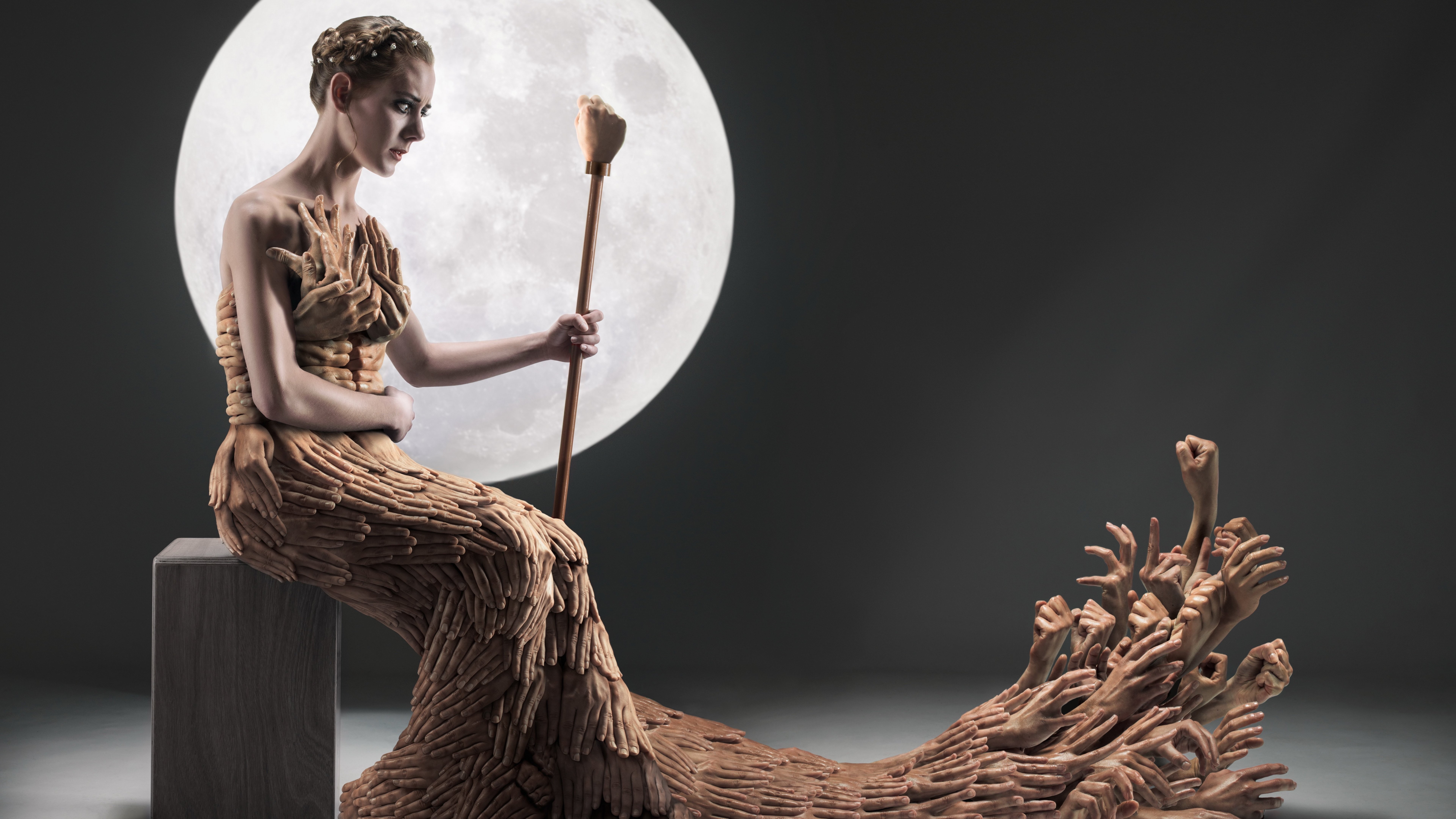 Woman in a dress made of hands holding a staff in front of the moon HD Wallpaper