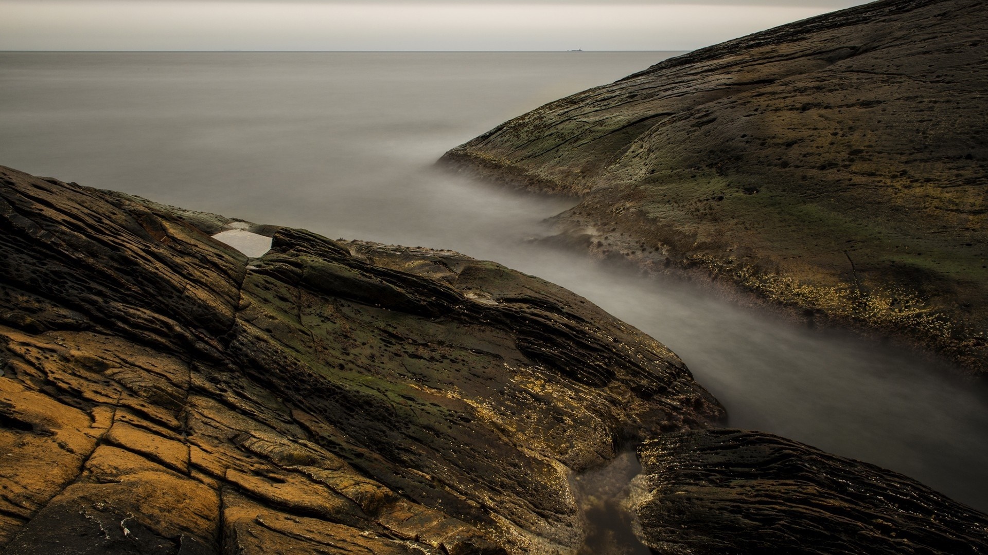 Rocky coastline with misty ocean water HD Wallpaper