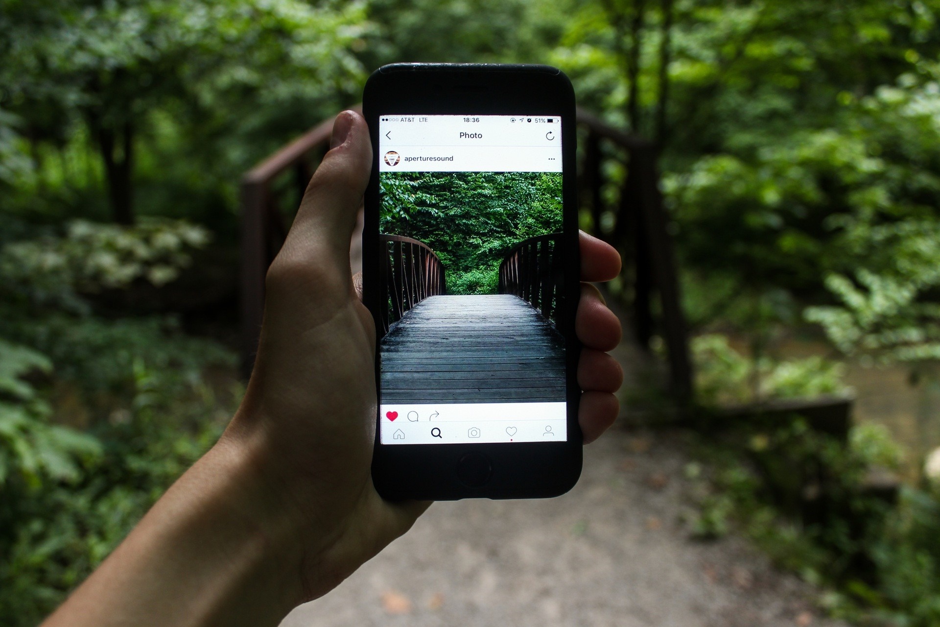 Hand holding phone showing Instagram photo of bridge HD Wallpaper
