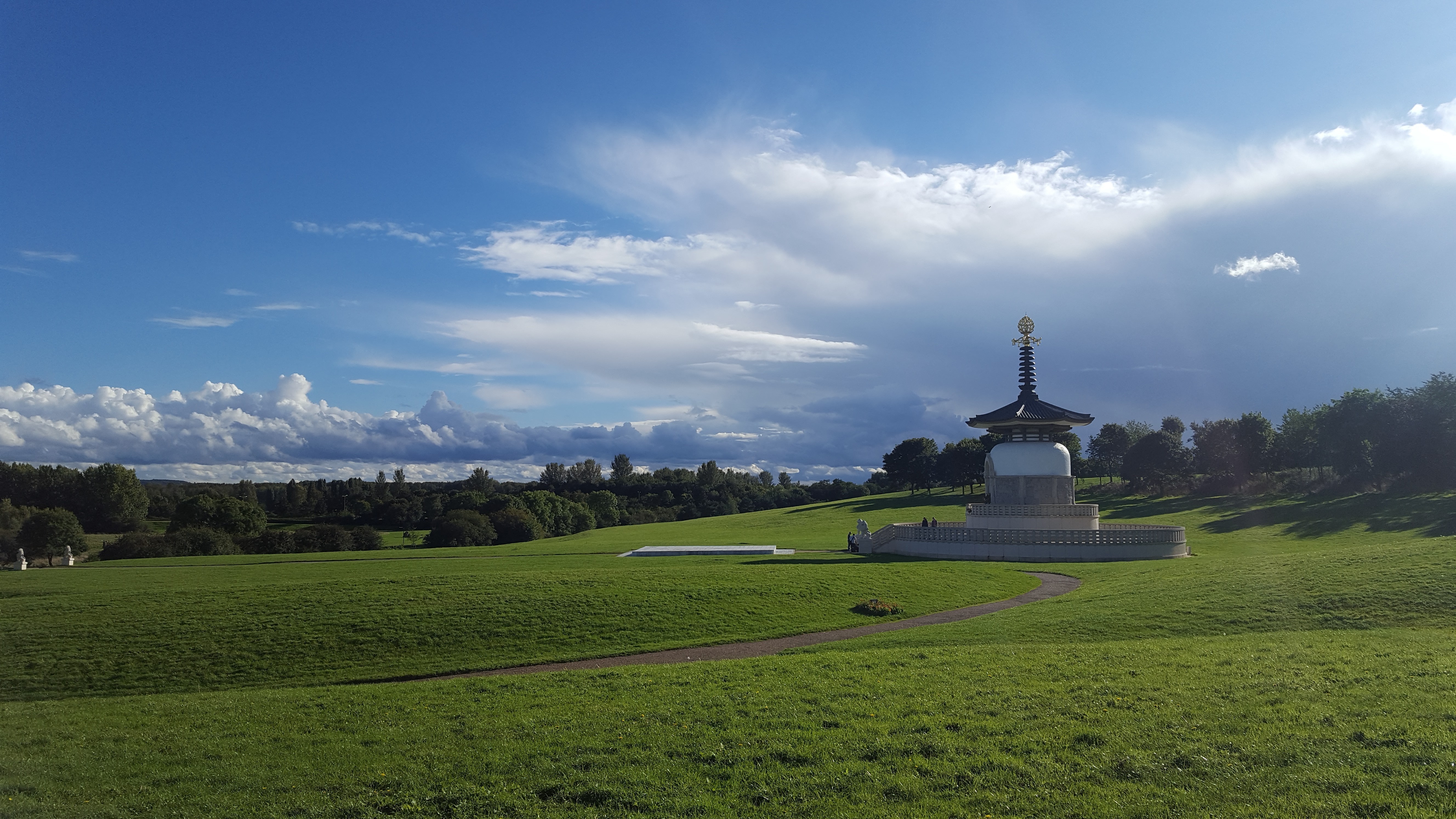 Pagoda in a grassy field under a cloudy sky HD Wallpaper