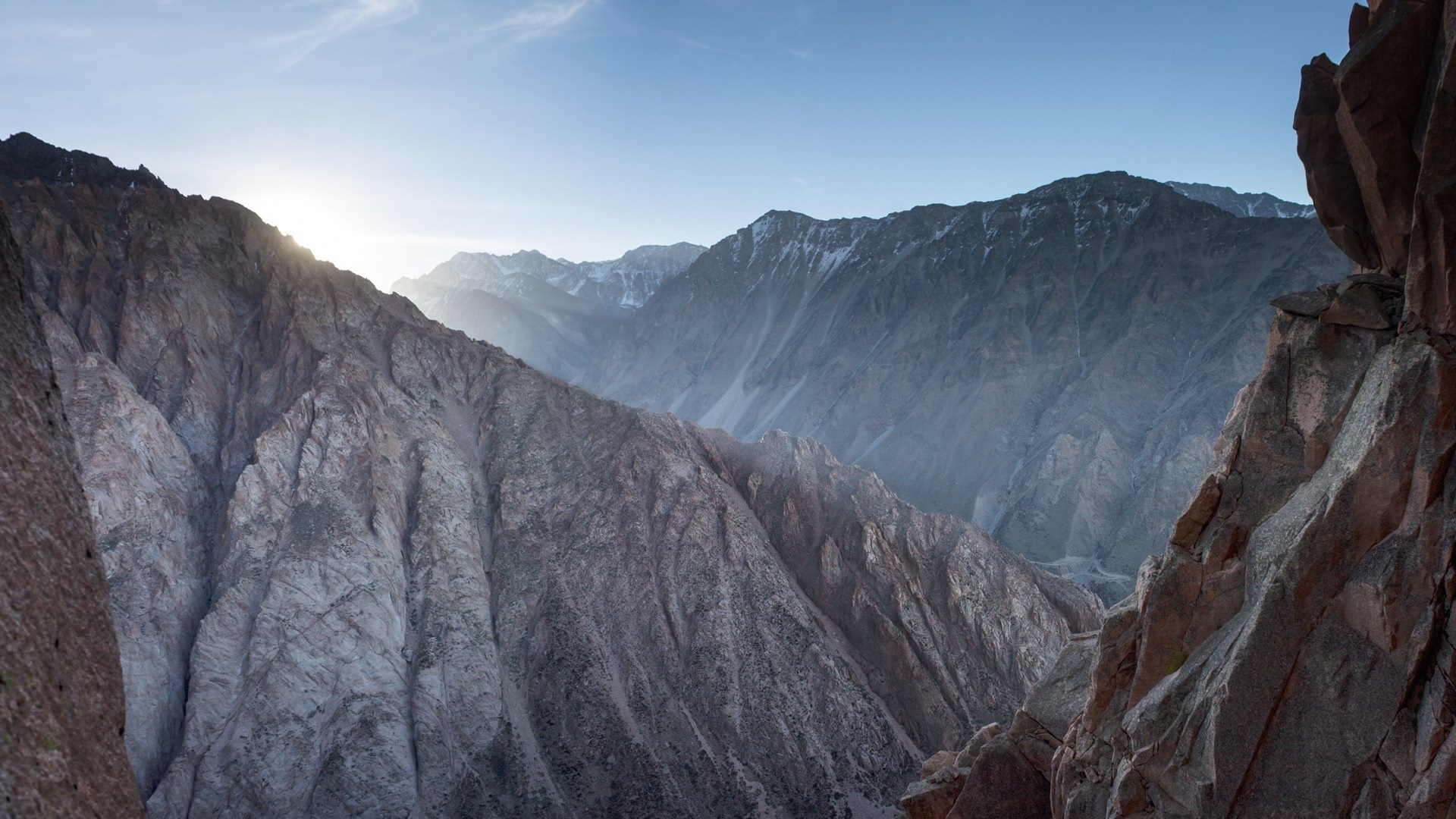 Mountain range with sunlit peaks and rocky foreground HD Wallpaper