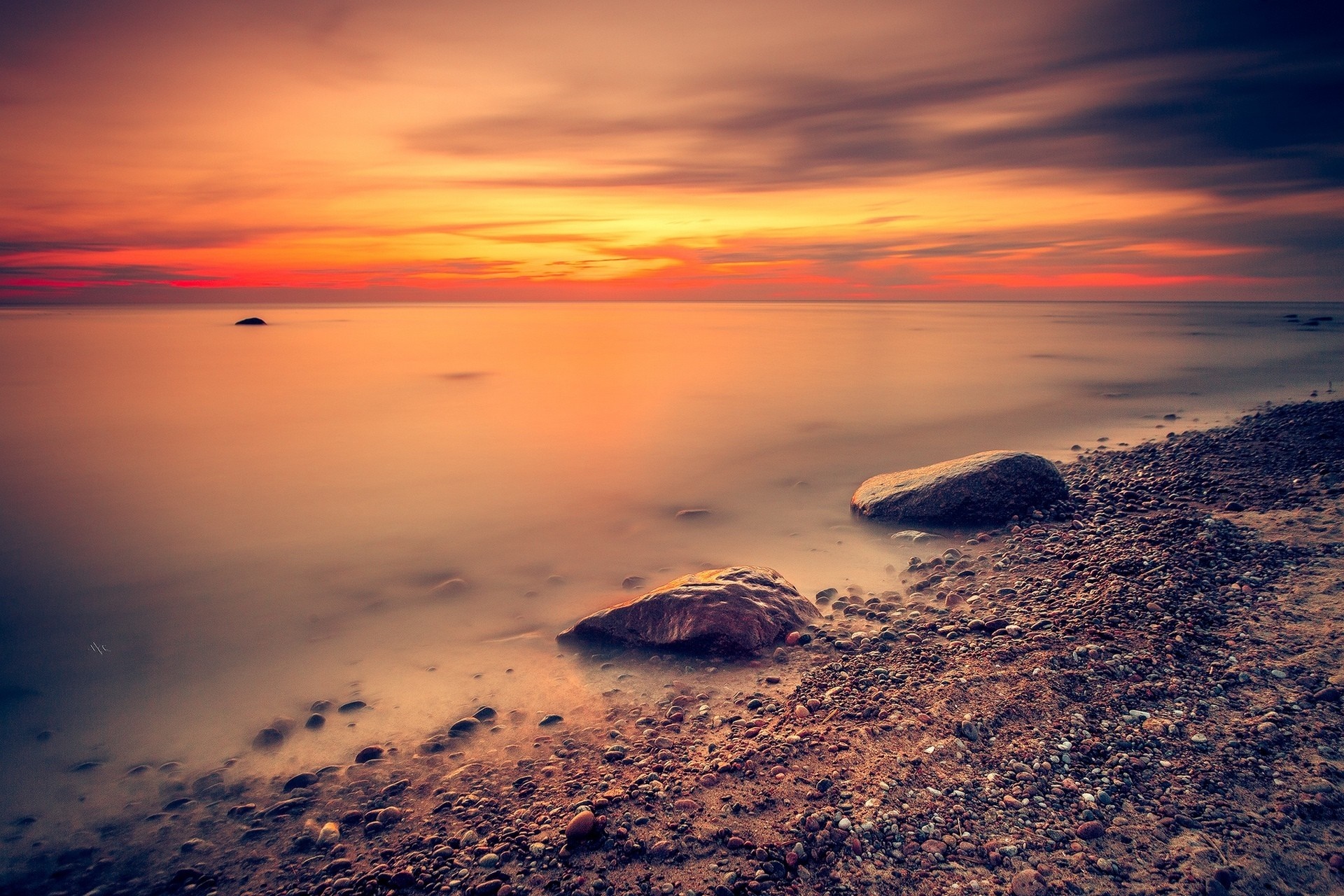 Sunset over the sea with rocks on the beach HD Wallpaper