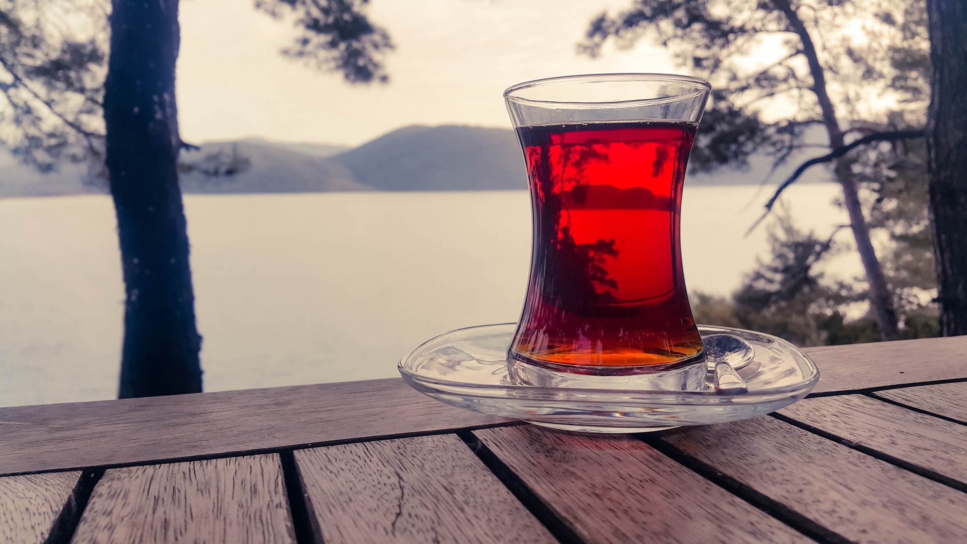 Glass of red tea on a table by the water HD Wallpaper