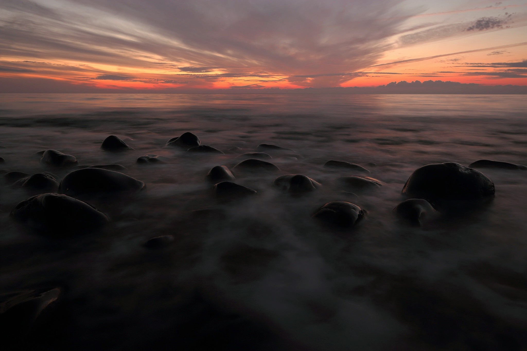 Sunset over the ocean with rocks and mist HD Wallpaper