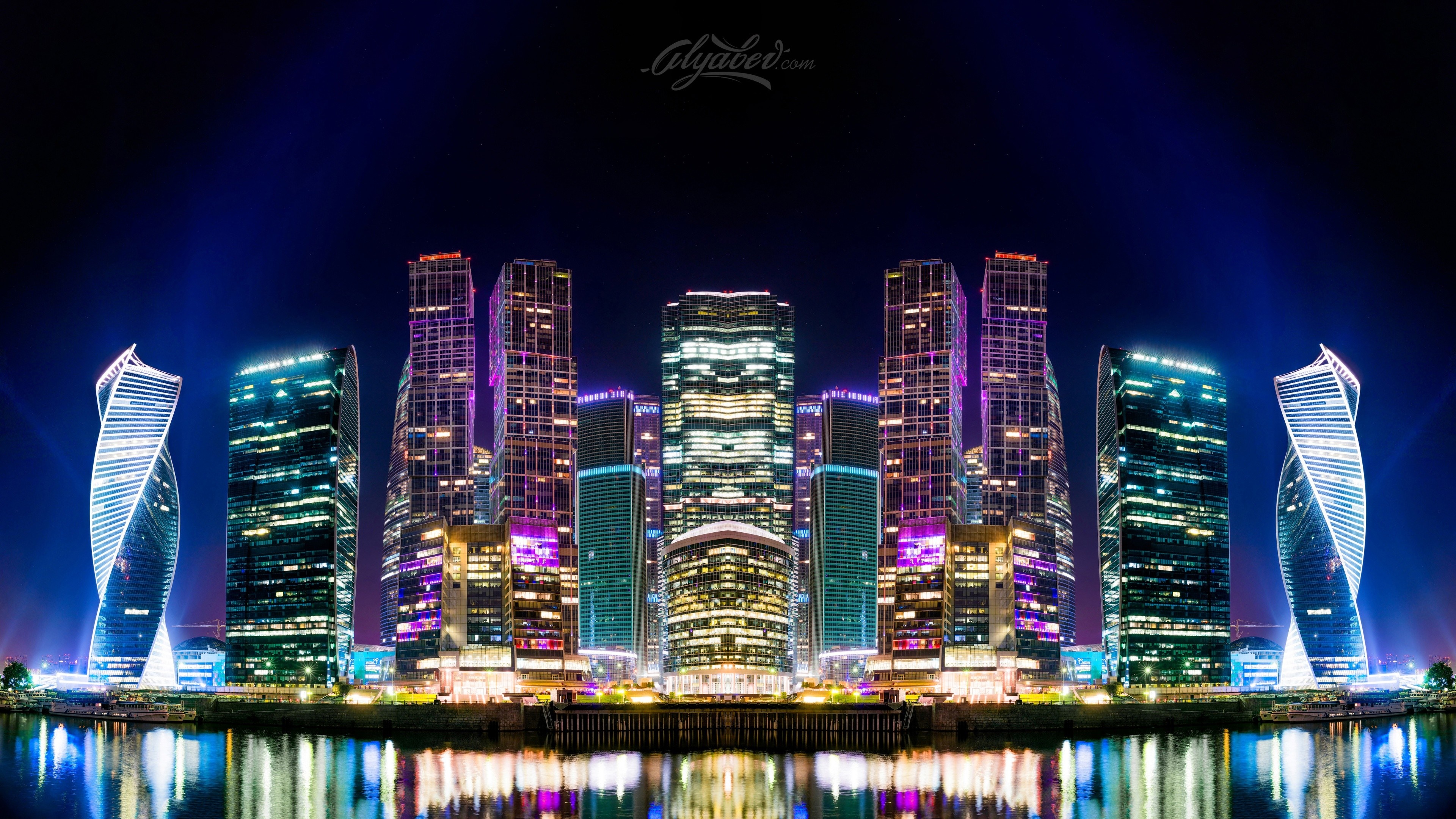 Cityscape with illuminated skyscrapers at night reflected in water HD Wallpaper