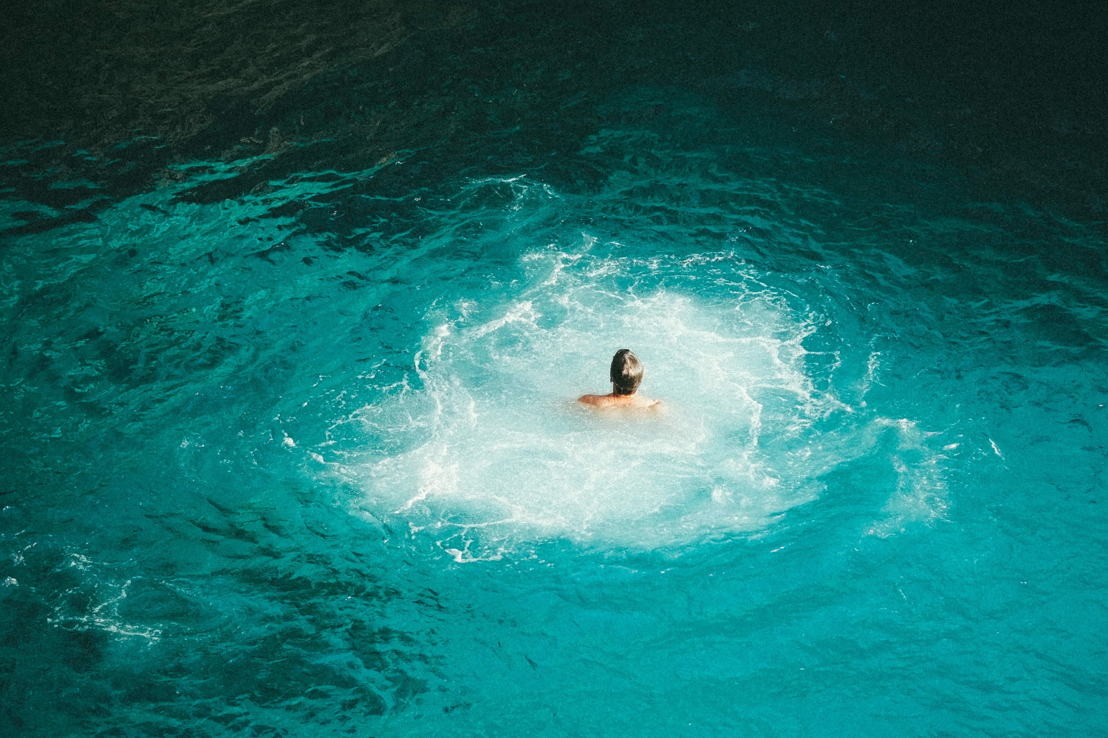 Person swimming in turquoise ocean water HD Wallpaper