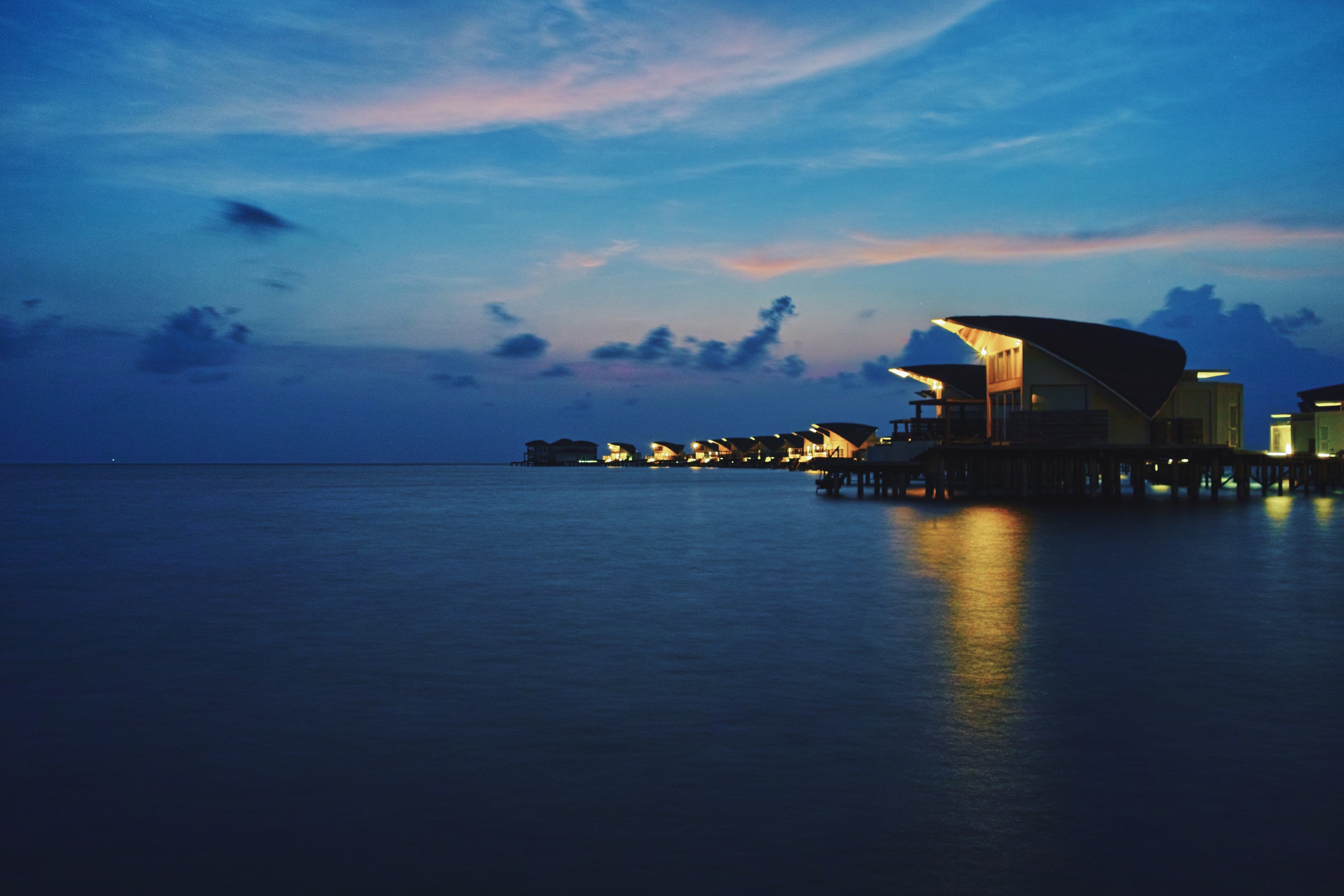 Overwater bungalows at dusk with ocean and sky HD Wallpaper
