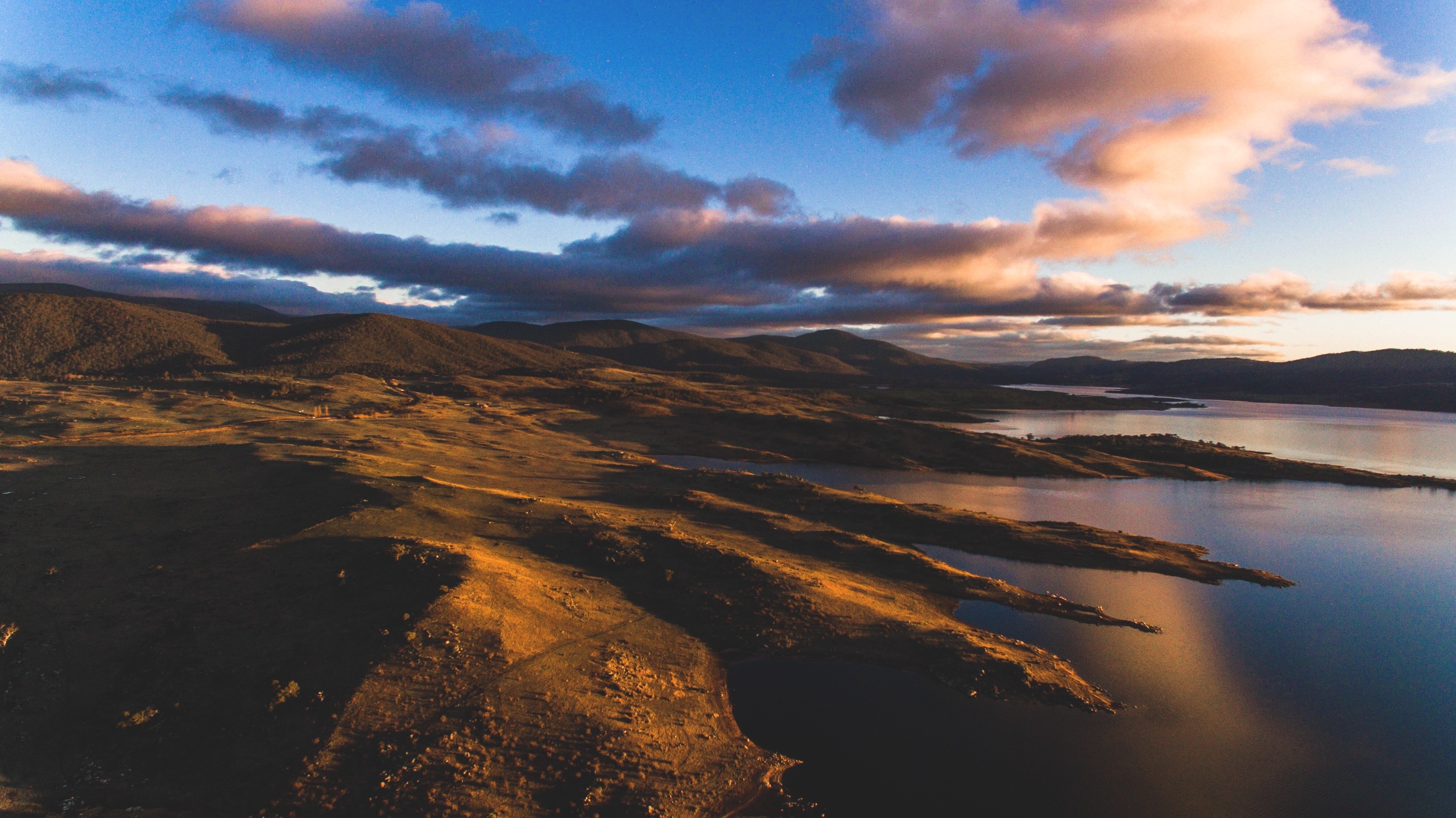 Sunset over a vast landscape with mountains and a lake HD Wallpaper