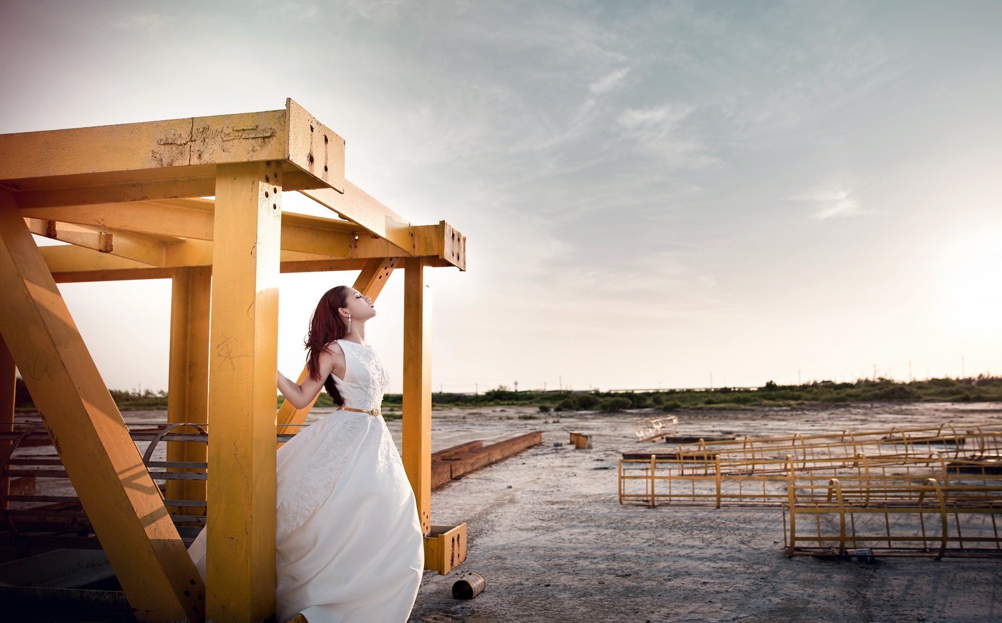 Woman in white dress standing near yellow structure outdoors HD Wallpaper