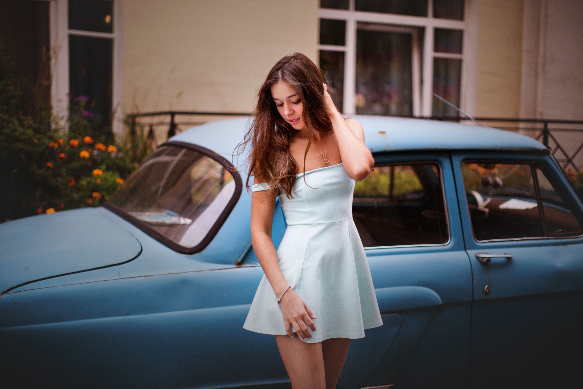 Woman in a light blue dress posing by a vintage blue car HD Wallpaper