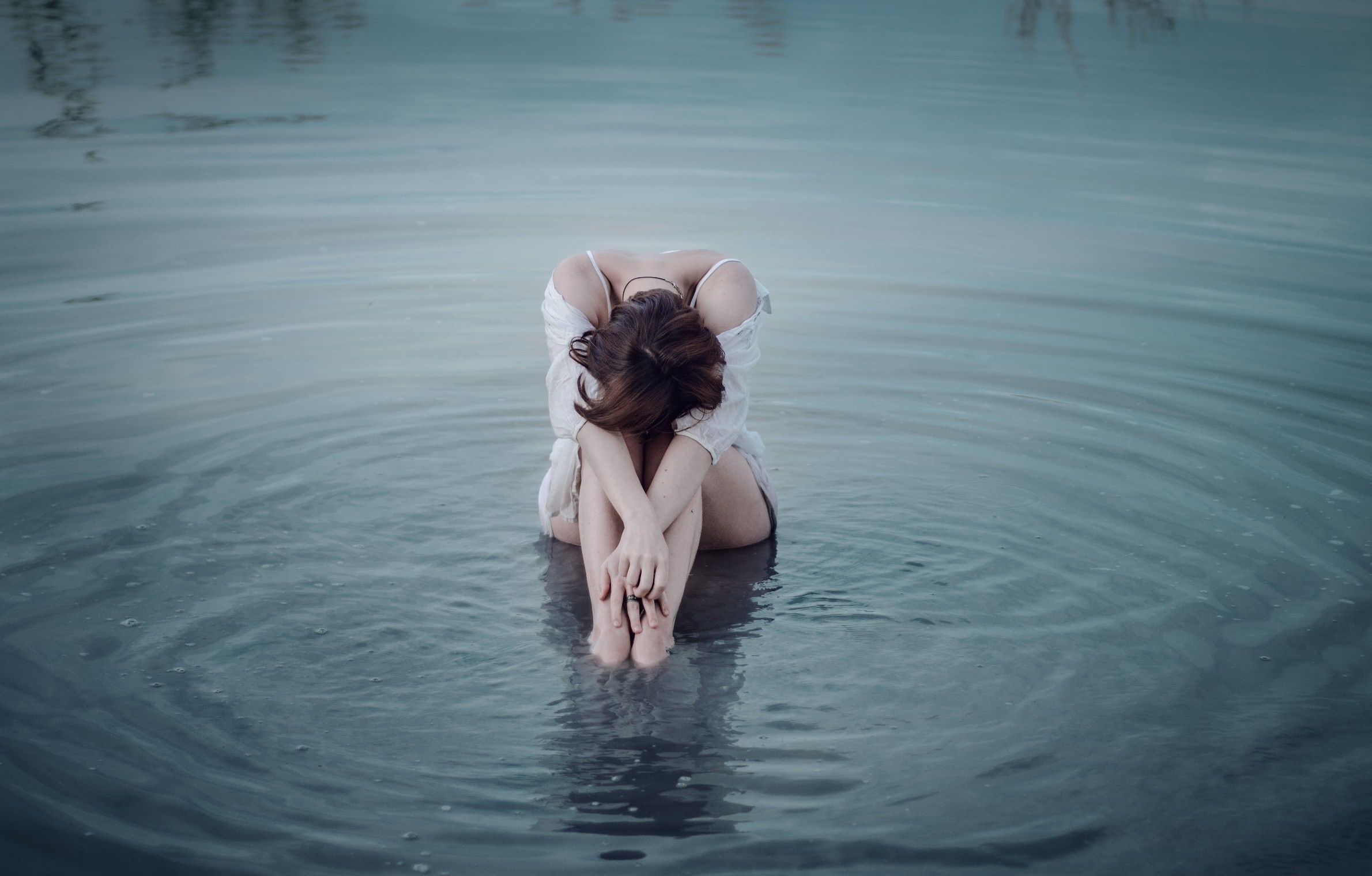 Woman sitting in water with head down HD Wallpaper