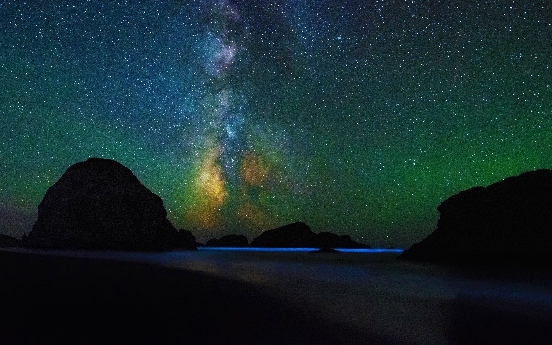 Milky Way over rocky coast with bioluminescent waves HD Wallpaper