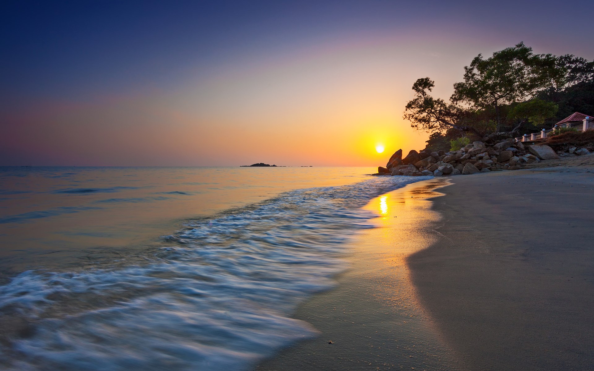 Sunset over a tropical beach with waves and rocks HD Wallpaper