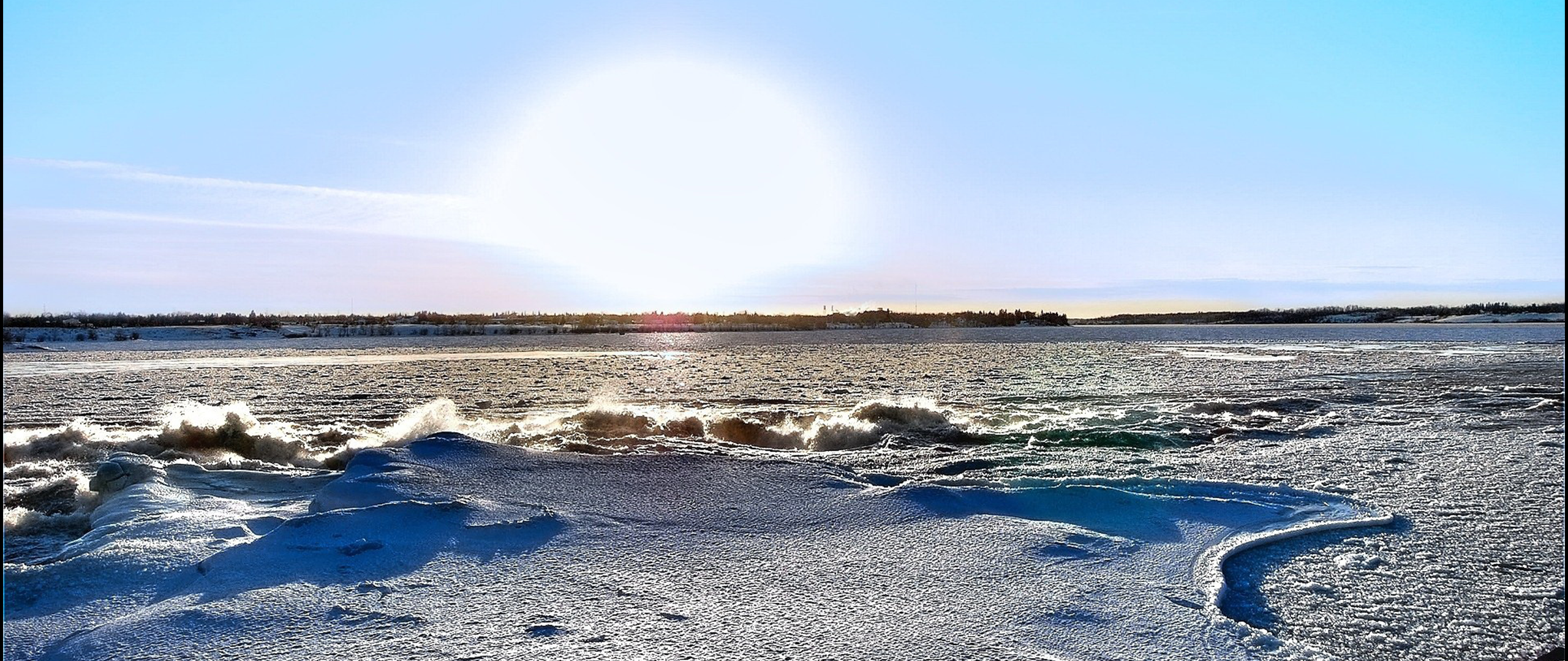 Winter scene with sun over icy water and snow-covered shore HD Wallpaper