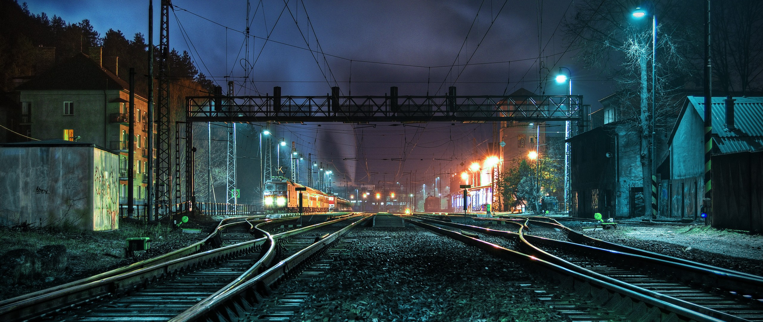 Train station at night with electric trains and tracks HD Wallpaper