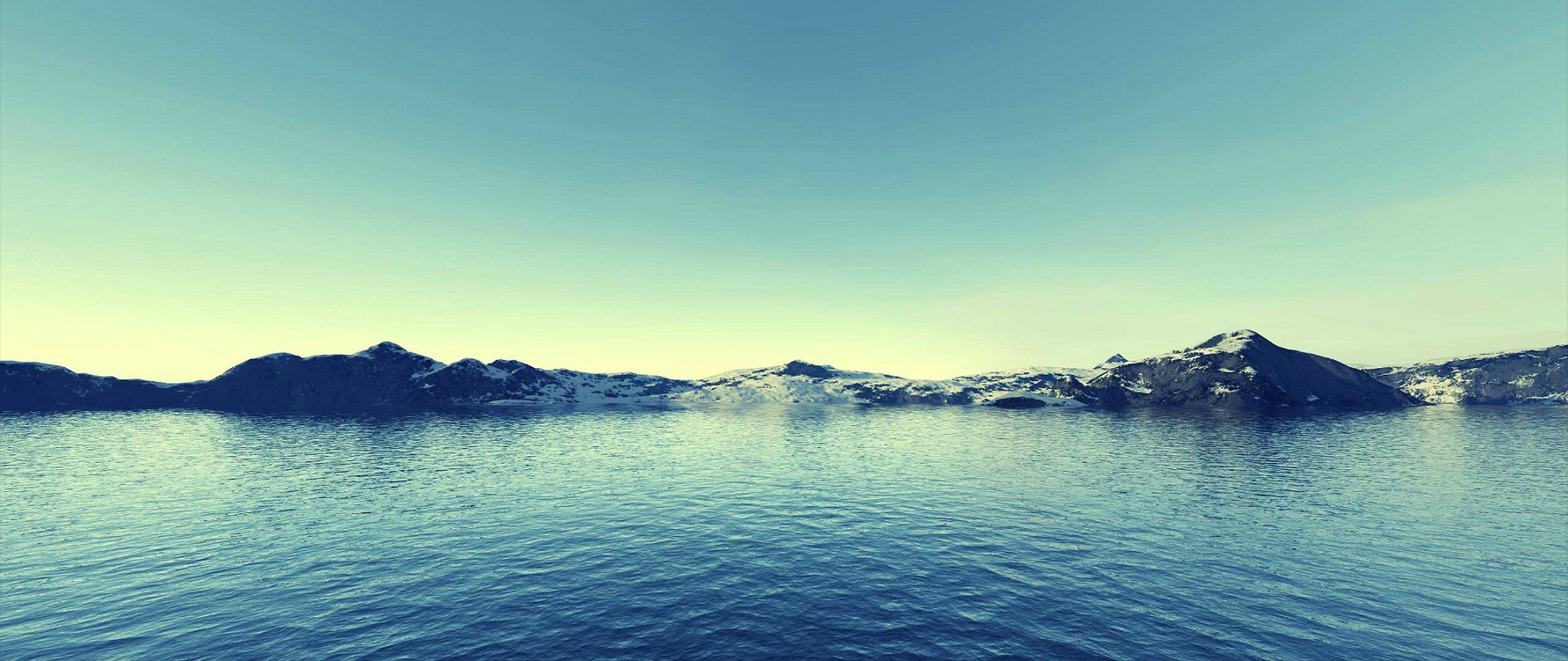 Panoramic view of a calm body of water with snow-capped mountains under a clear sky HD Wallpaper