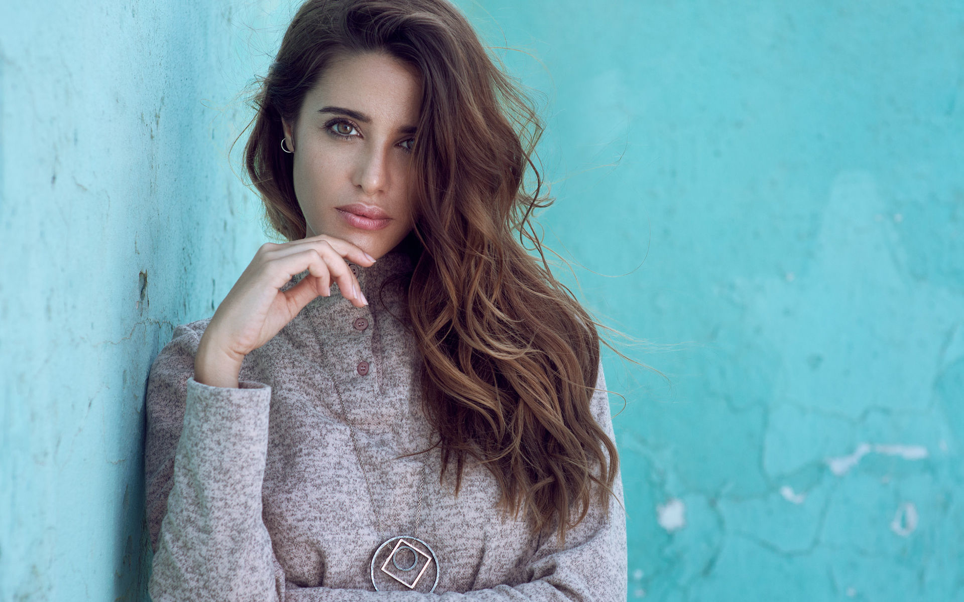 Woman with long brown hair leaning against a blue wall HD Wallpaper
