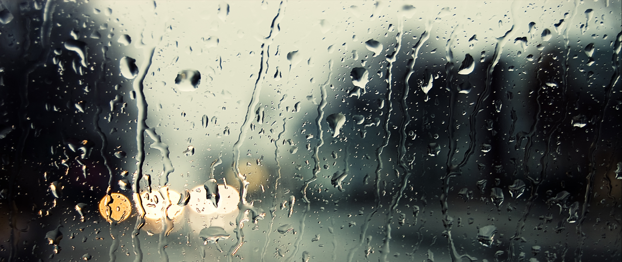 Raindrops on a window with blurred lights HD Wallpaper