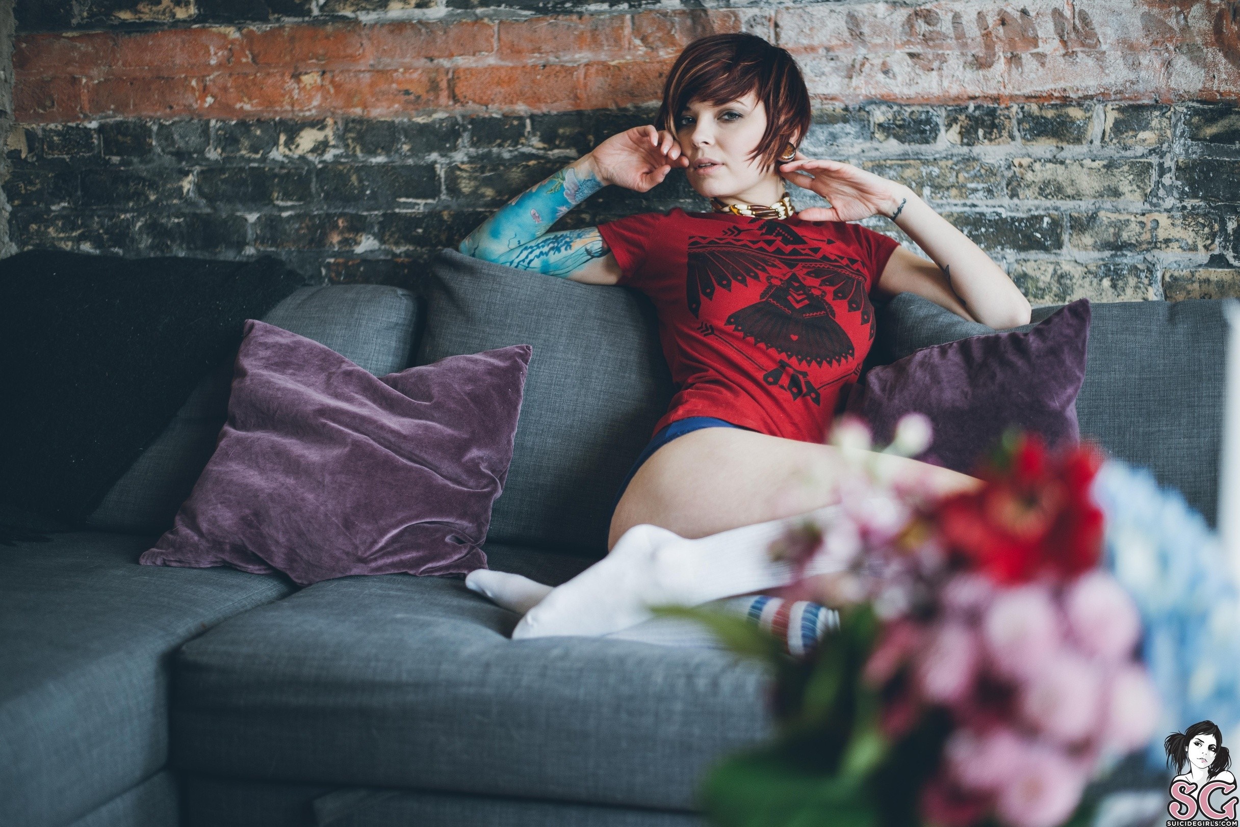 Woman with tattoos sitting on a couch HD Wallpaper