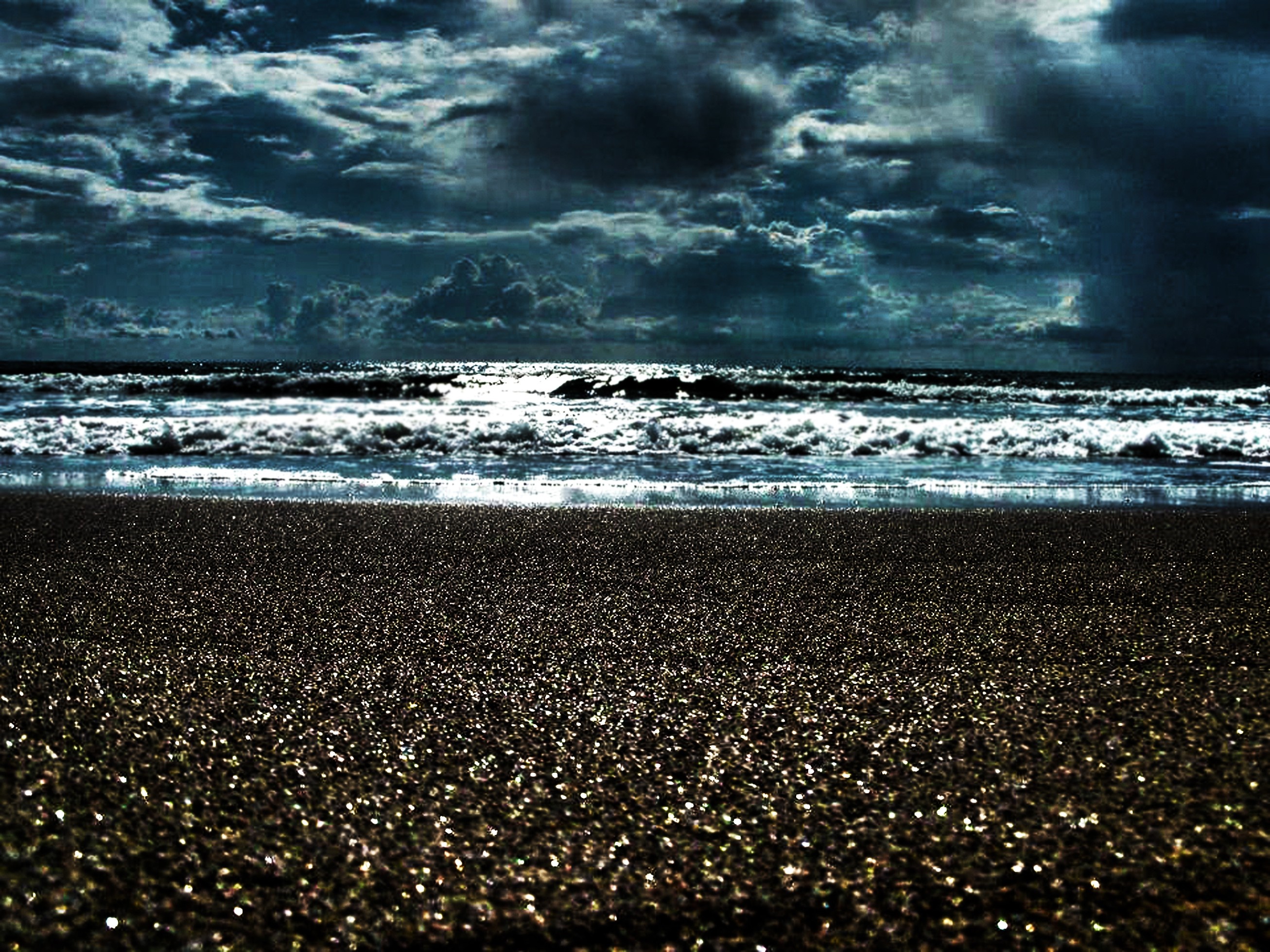 Dark stormy clouds over a beach with waves HD Wallpaper