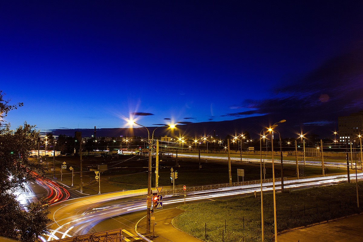 Cityscape at dusk with light trails on roads HD Wallpaper
