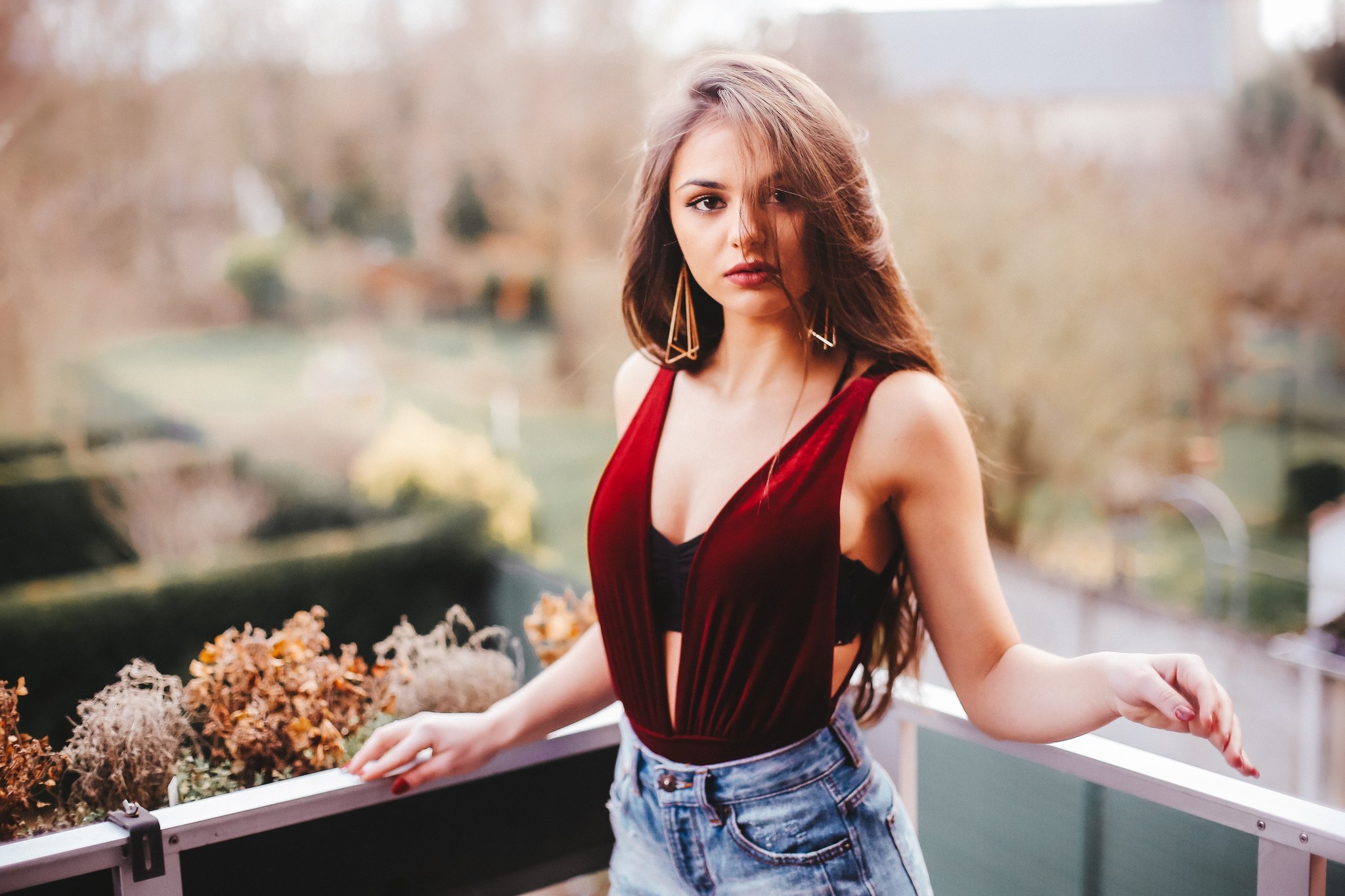 Woman in red bodysuit and denim shorts on a balcony HD Wallpaper
