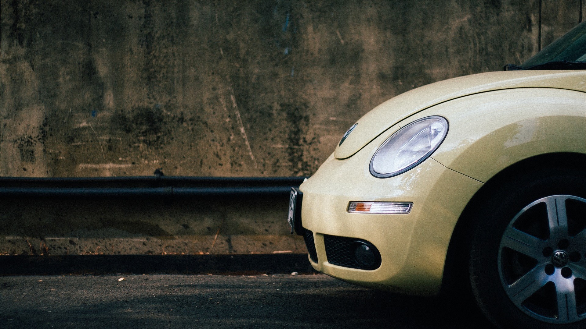 Yellow Volkswagen Beetle parked against a concrete wall HD Wallpaper