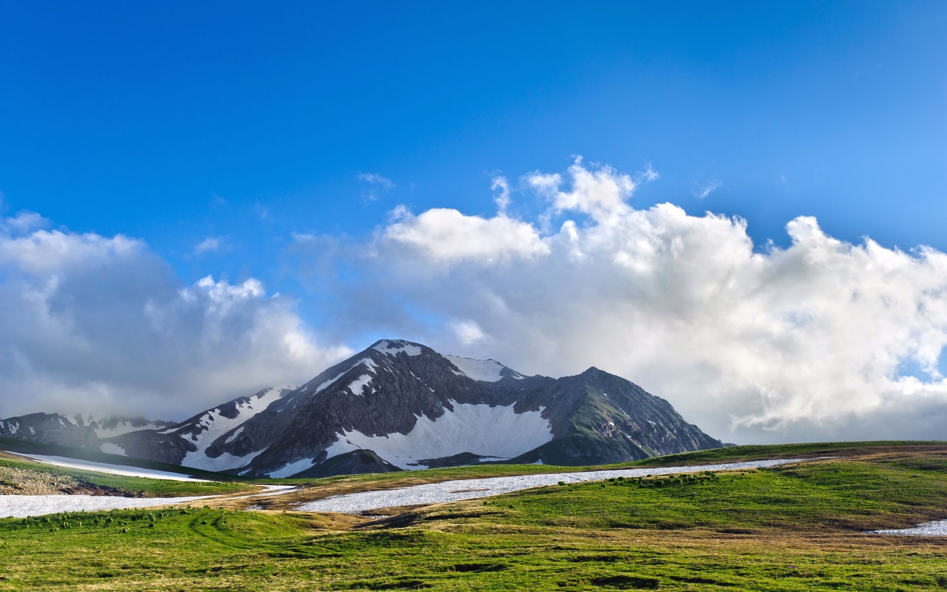 Snow-capped mountain range under a blue sky with clouds HD Wallpaper