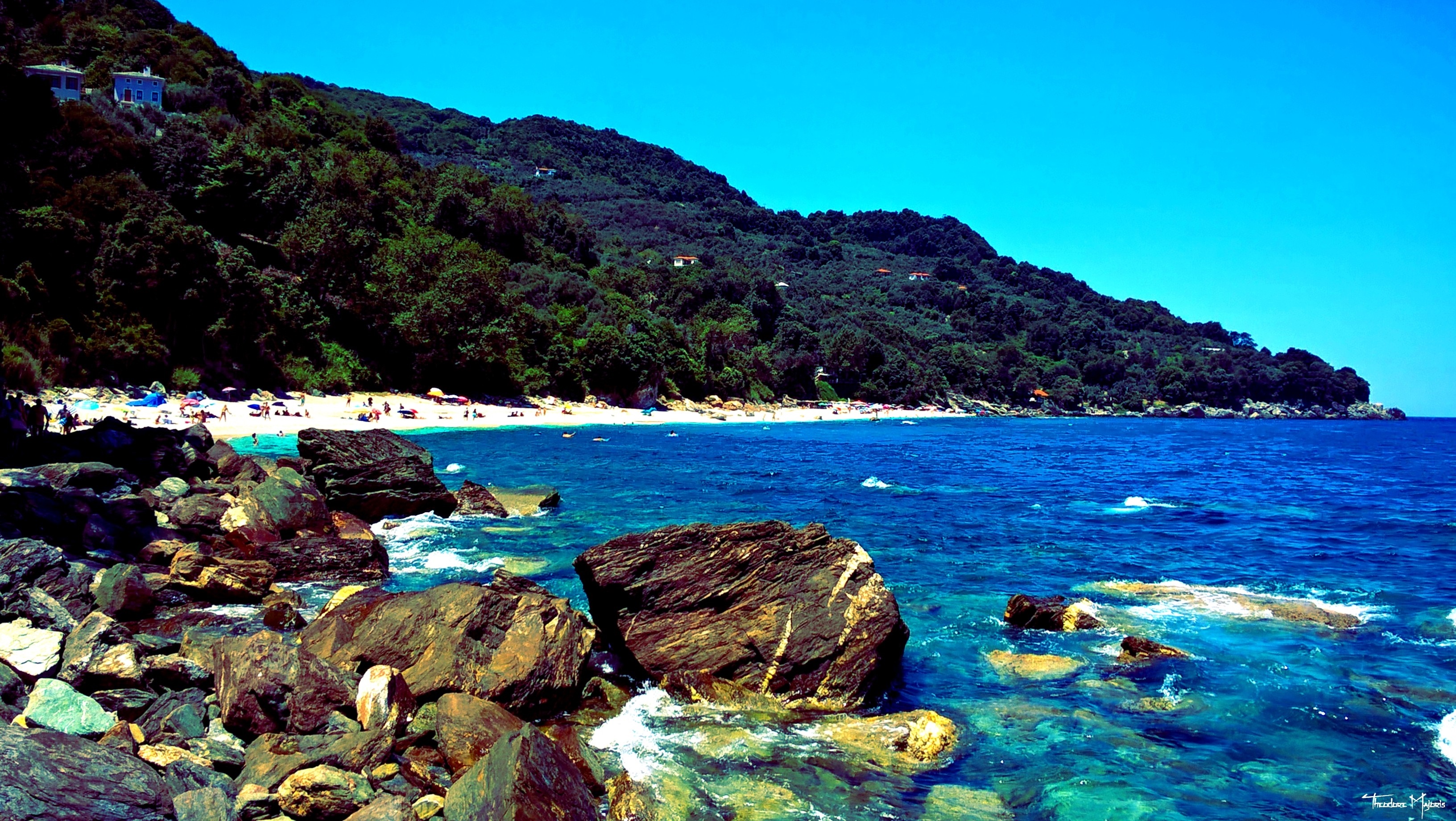 Rocky coast with a beach and forested mountain HD Wallpaper